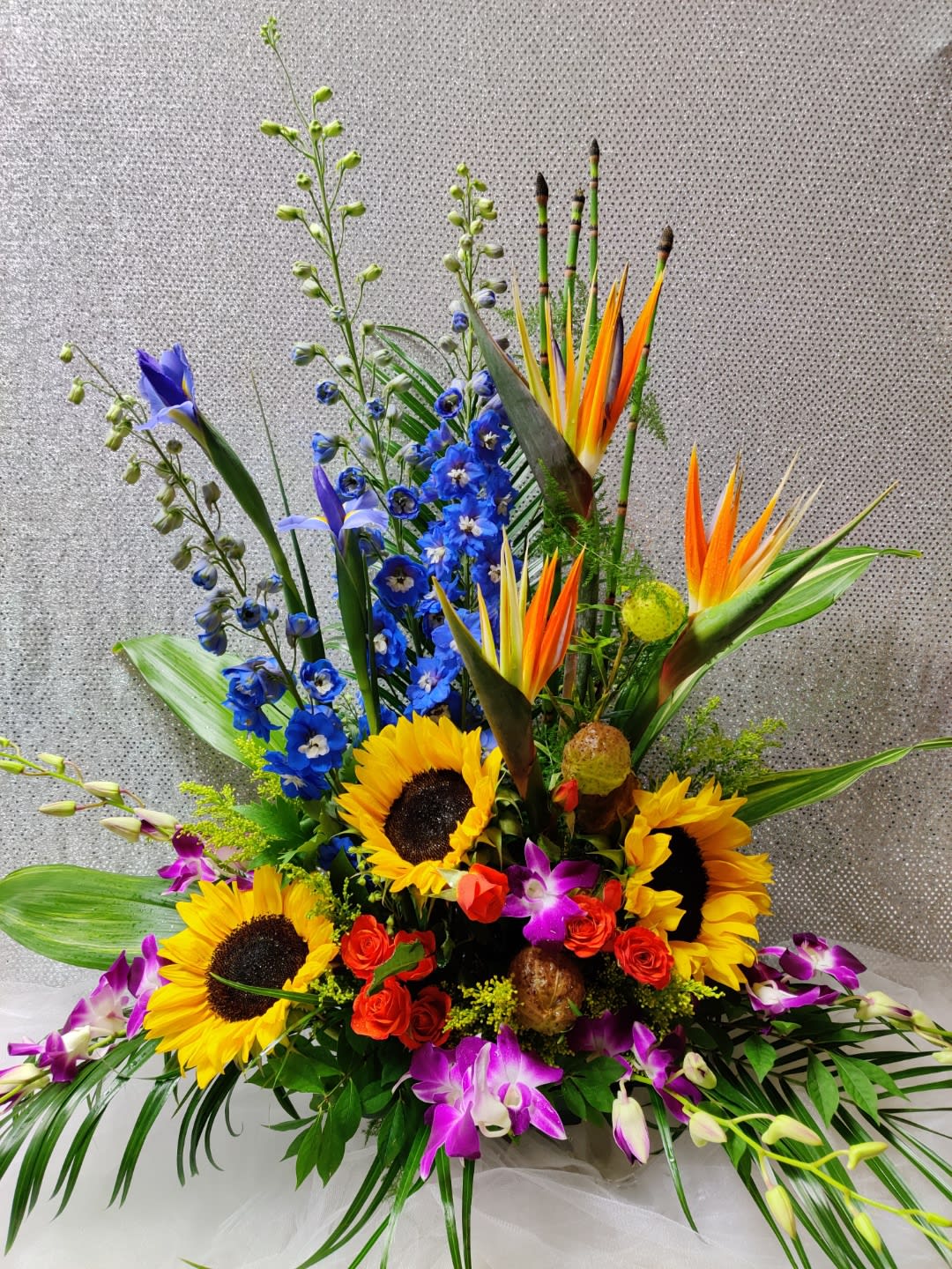 Colorful tropical bouquet with sunflowers, orchids, and blue flowers