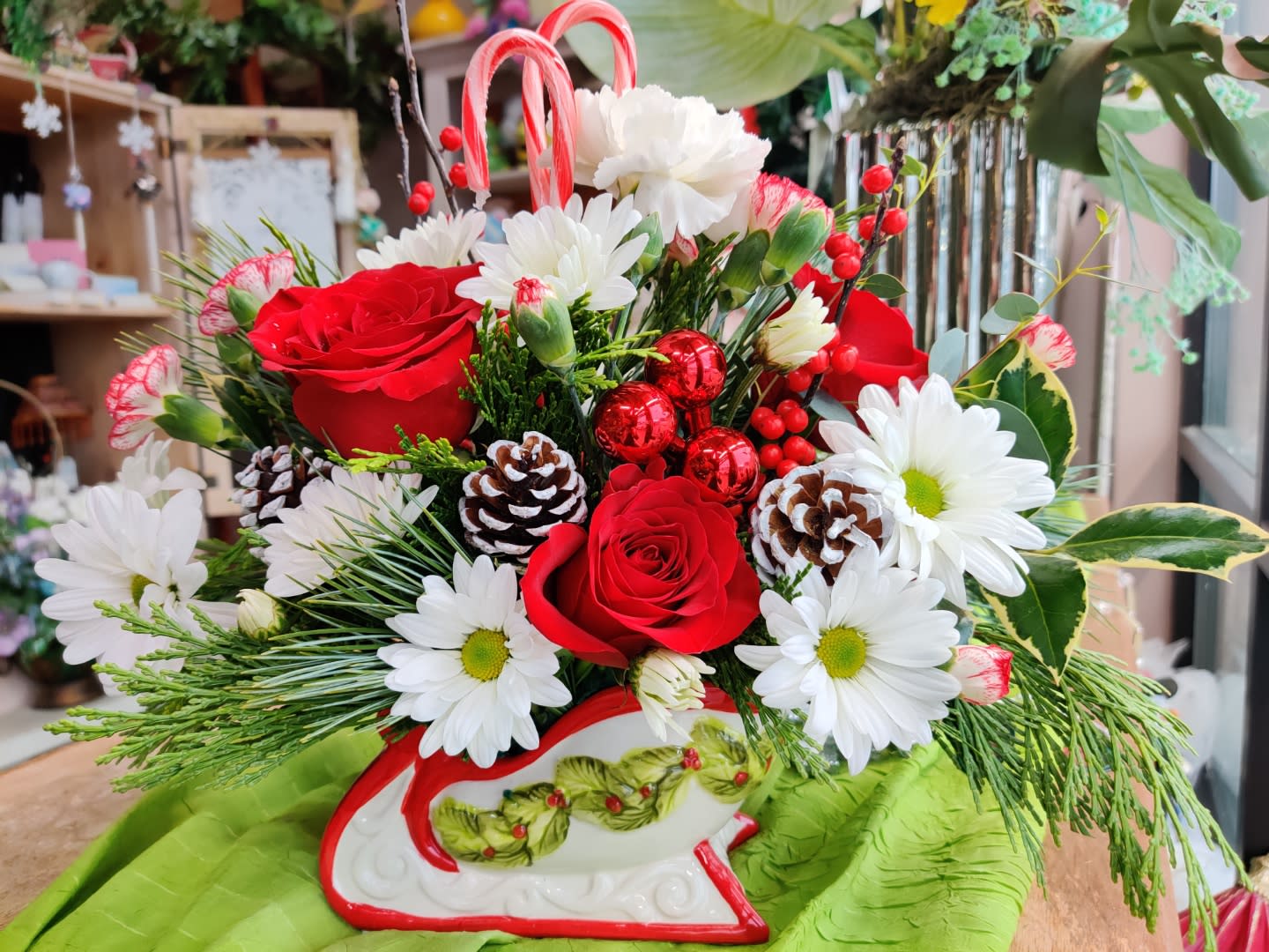 Red roses and white daisies arranged in a decorative sleigh container