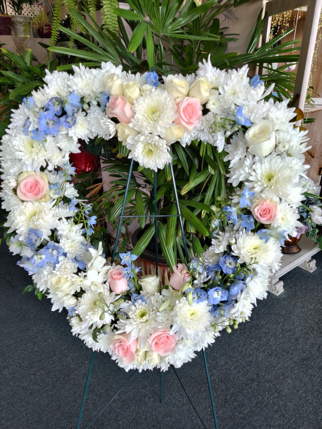 Heart-shaped floral wreath with white daisies, pink roses, and blue accents