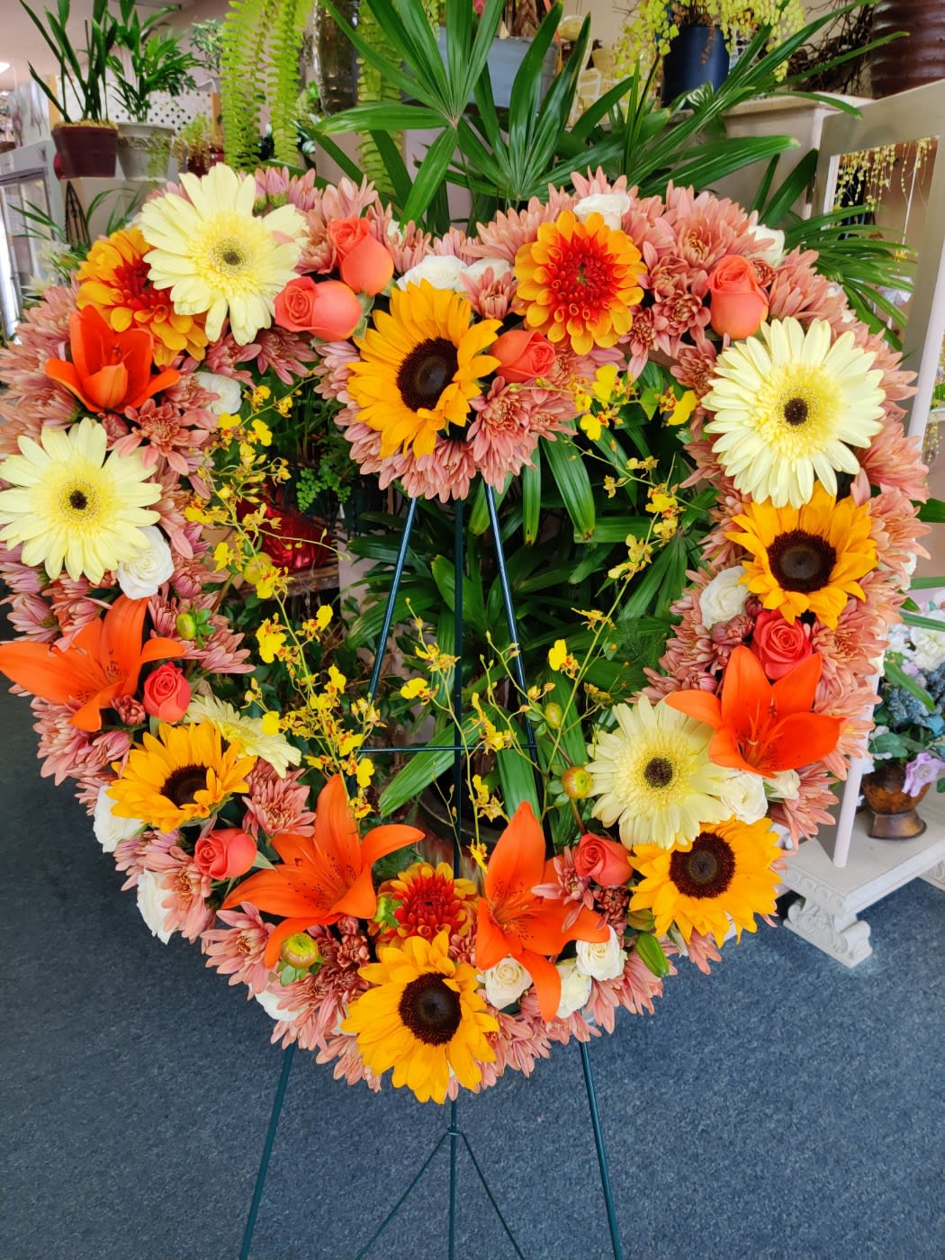 Heart-shaped floral wreath with sunflowers, lilies, roses, and gerbera daisies