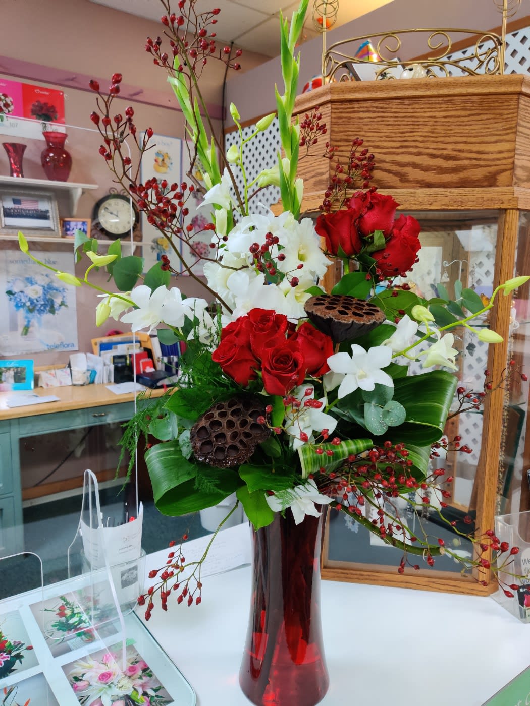 Red and white floral arrangement in a tall red vase