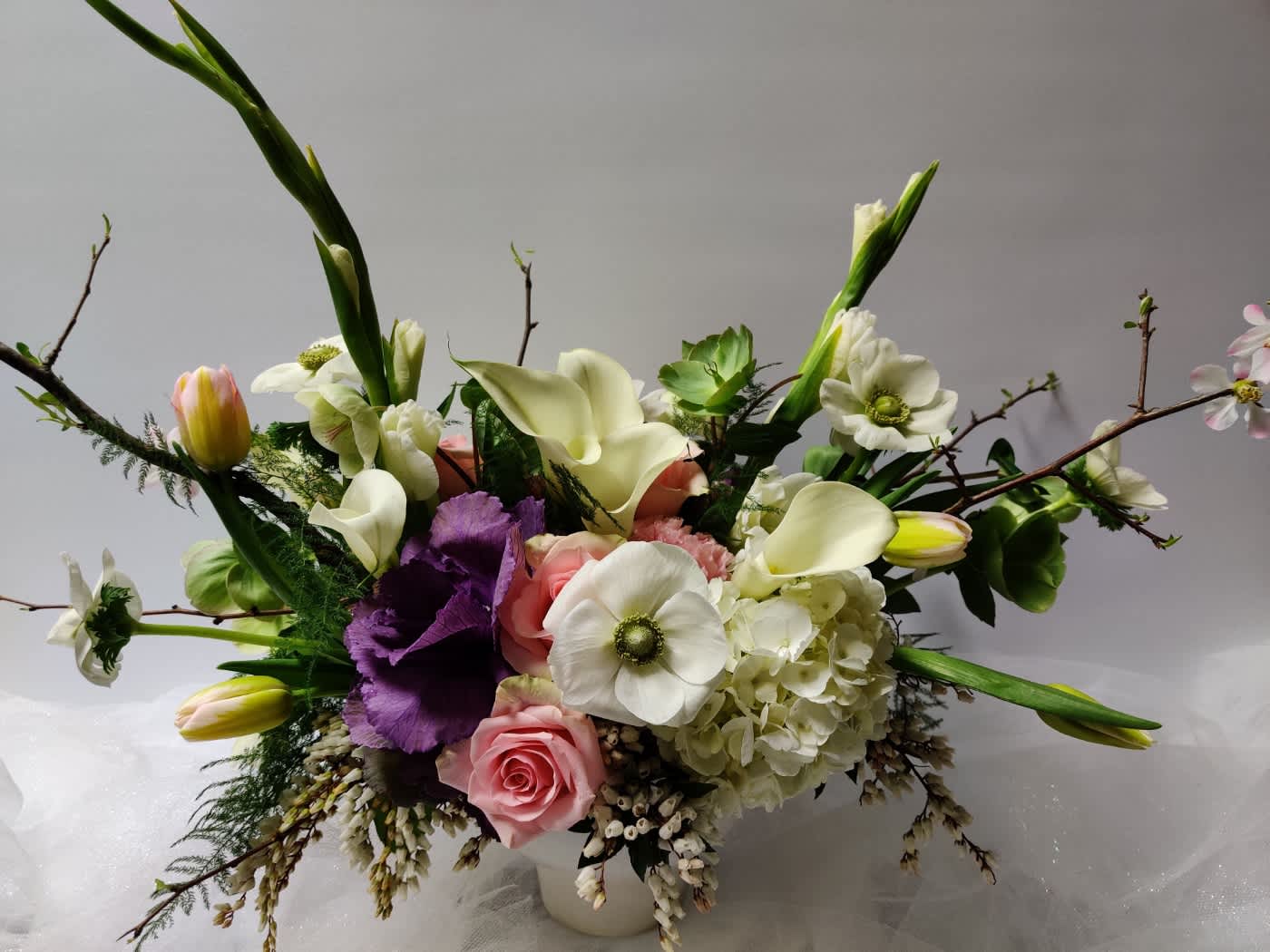Mixed bouquet with white calla lilies, pink roses, and purple blooms in a vase