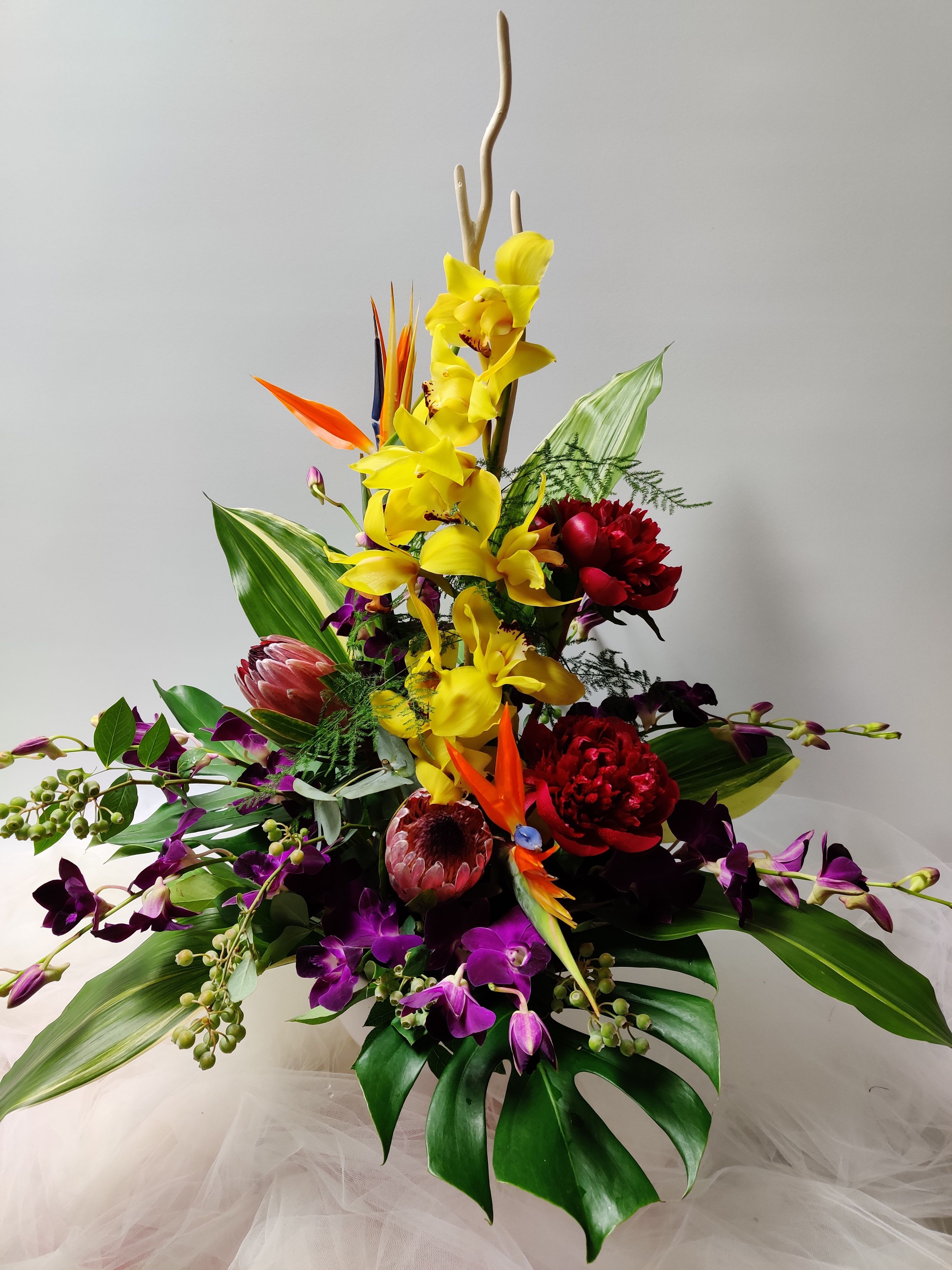 Tropical bouquet with yellow orchids, purple orchids, and red blooms