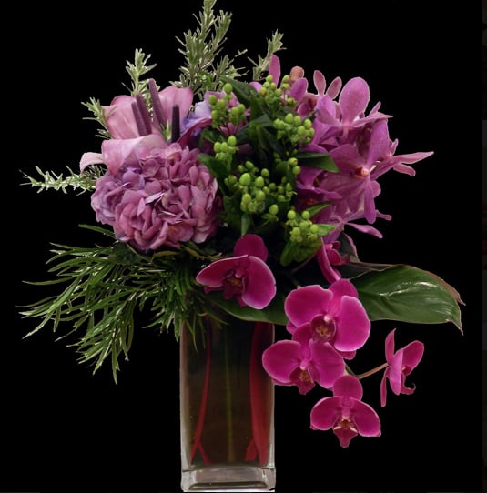 Pink and purple floral arrangement in a tall glass vase