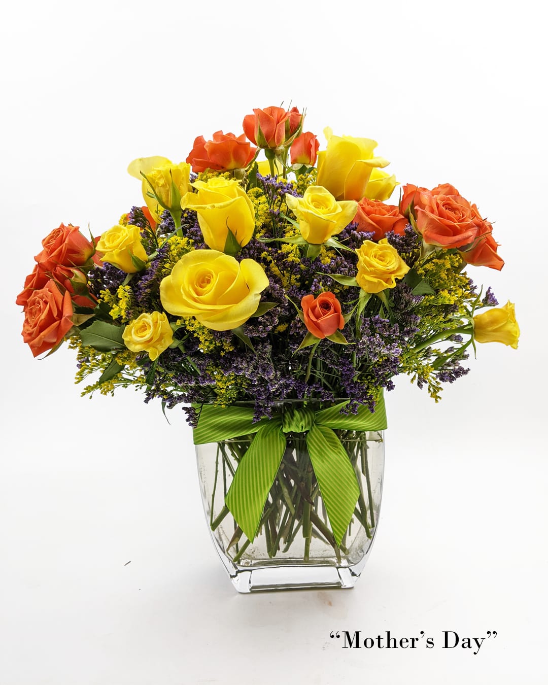 Yellow and orange roses in a clear glass vase with a green ribbon