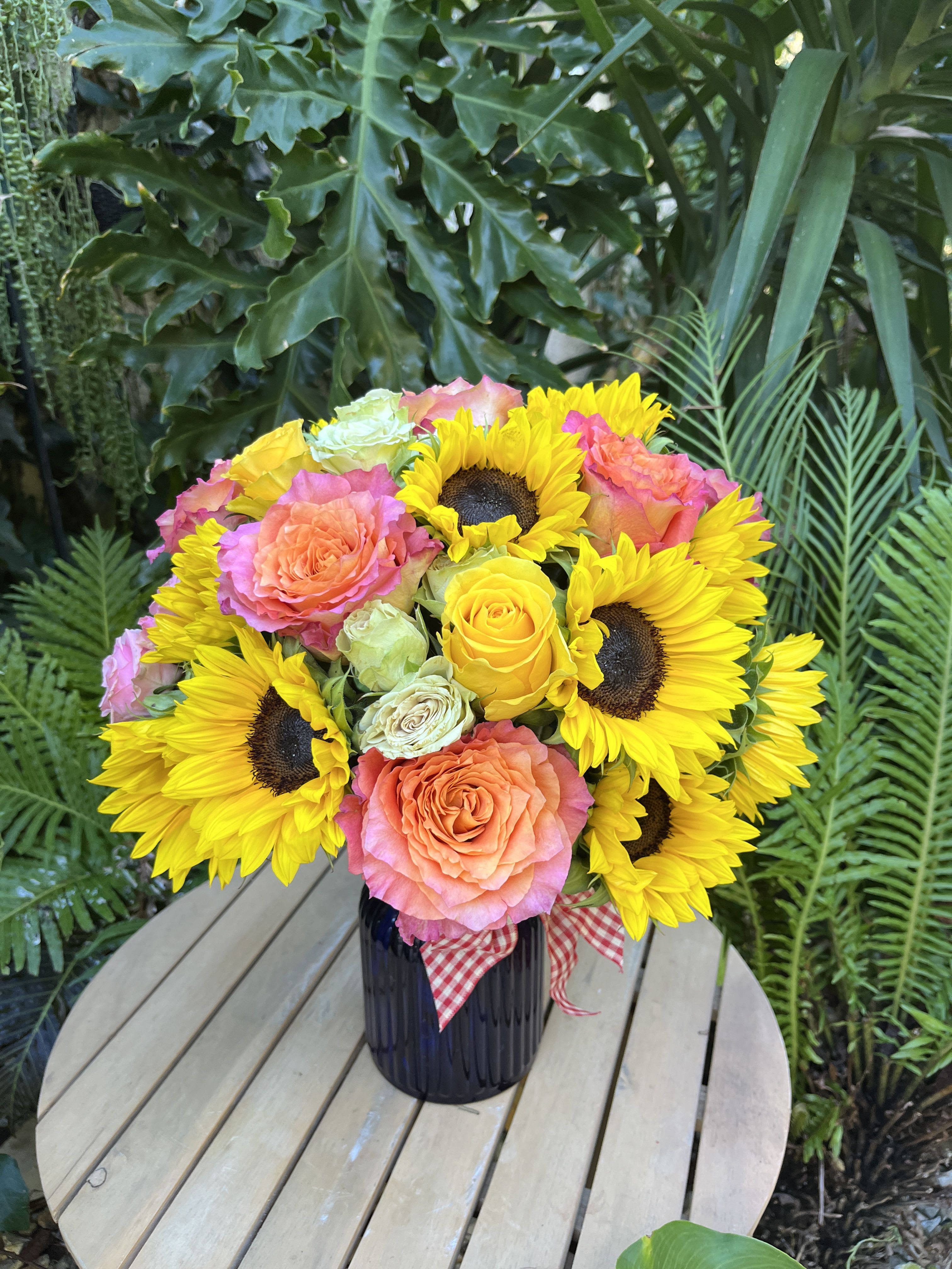 Bouquet of yellow sunflowers and peach roses in a dark vase