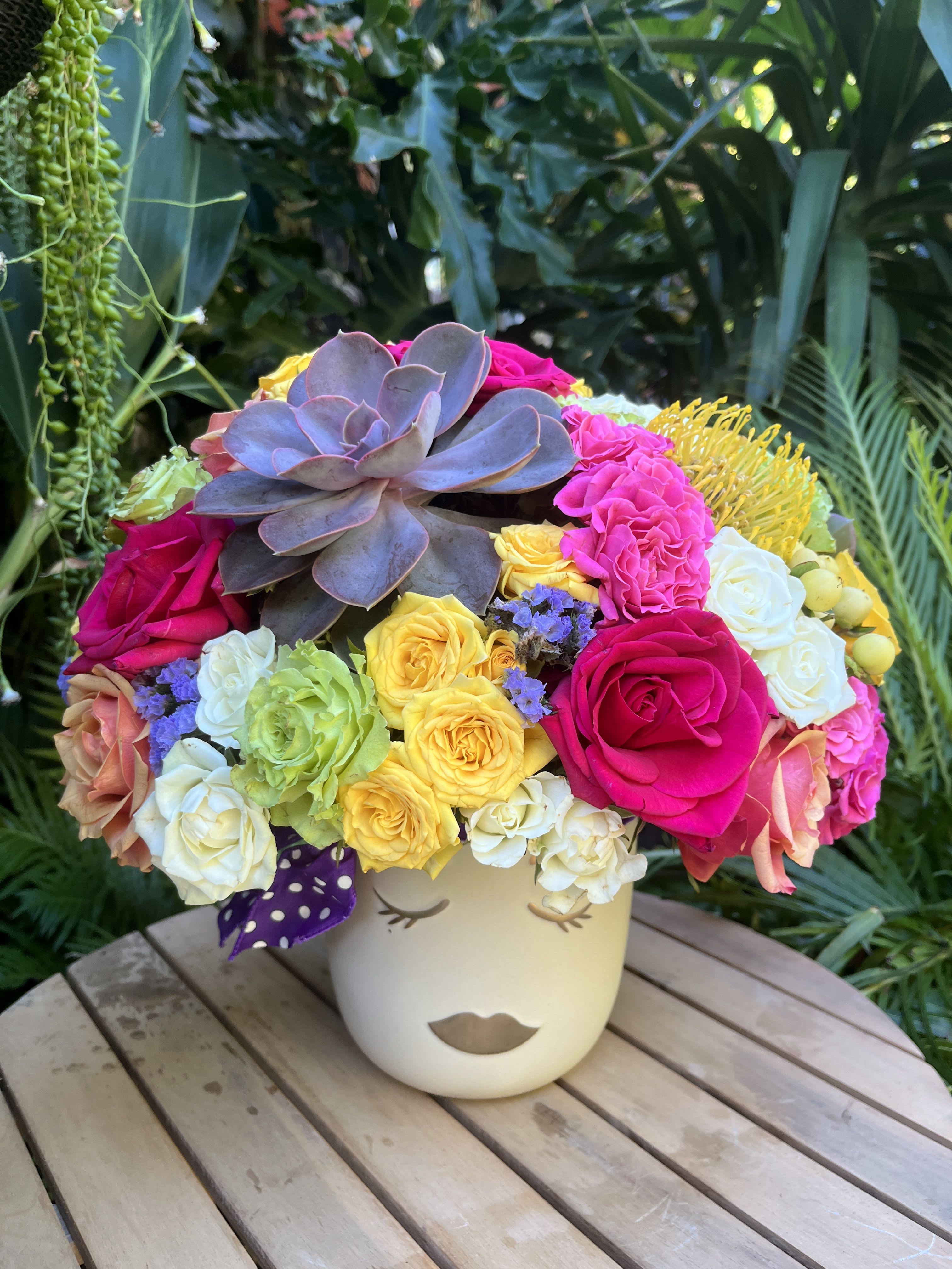 Colorful bouquet with roses and a large succulent in a face vase