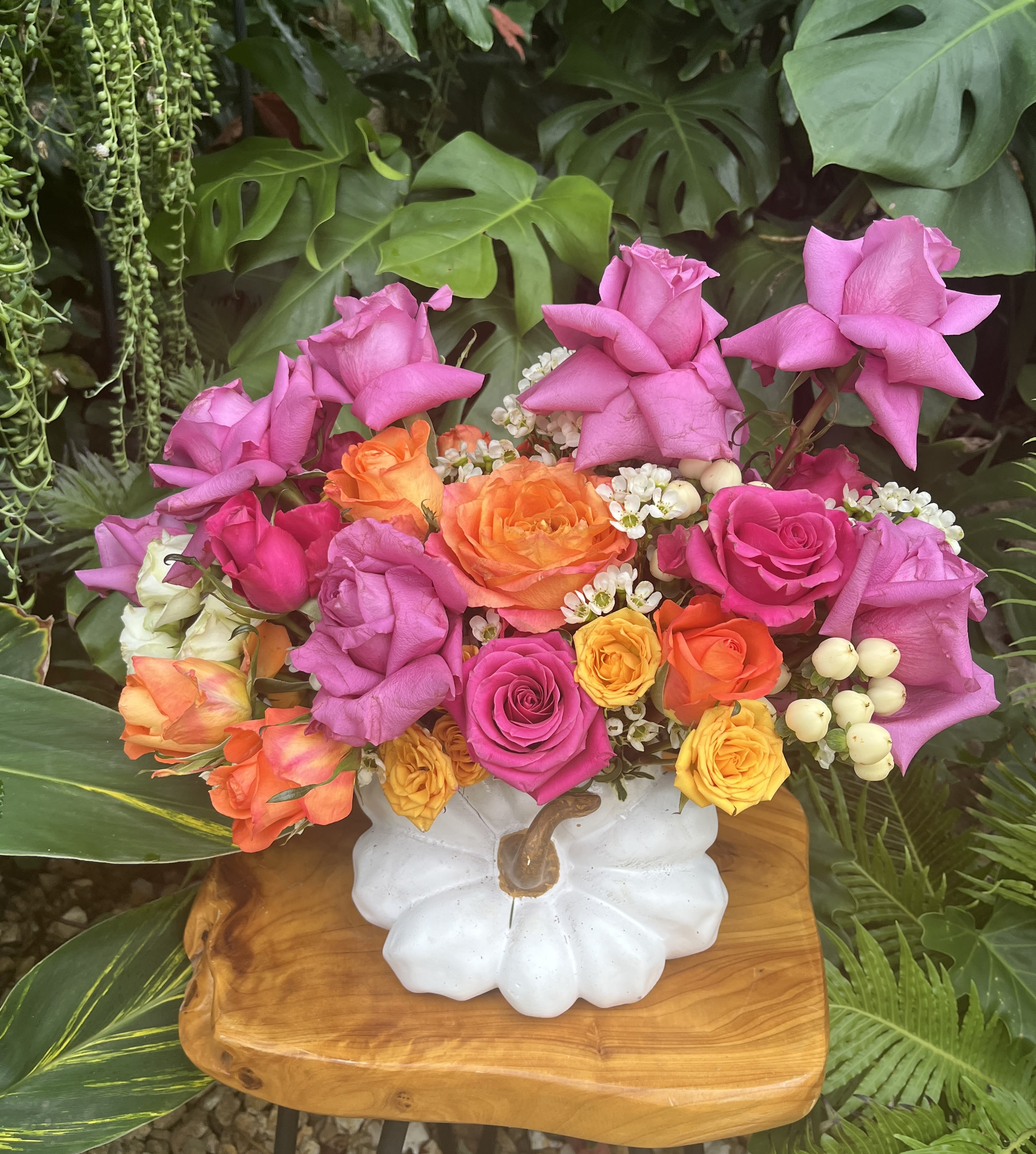 Bright mixed rose arrangement in a white pumpkin vase
