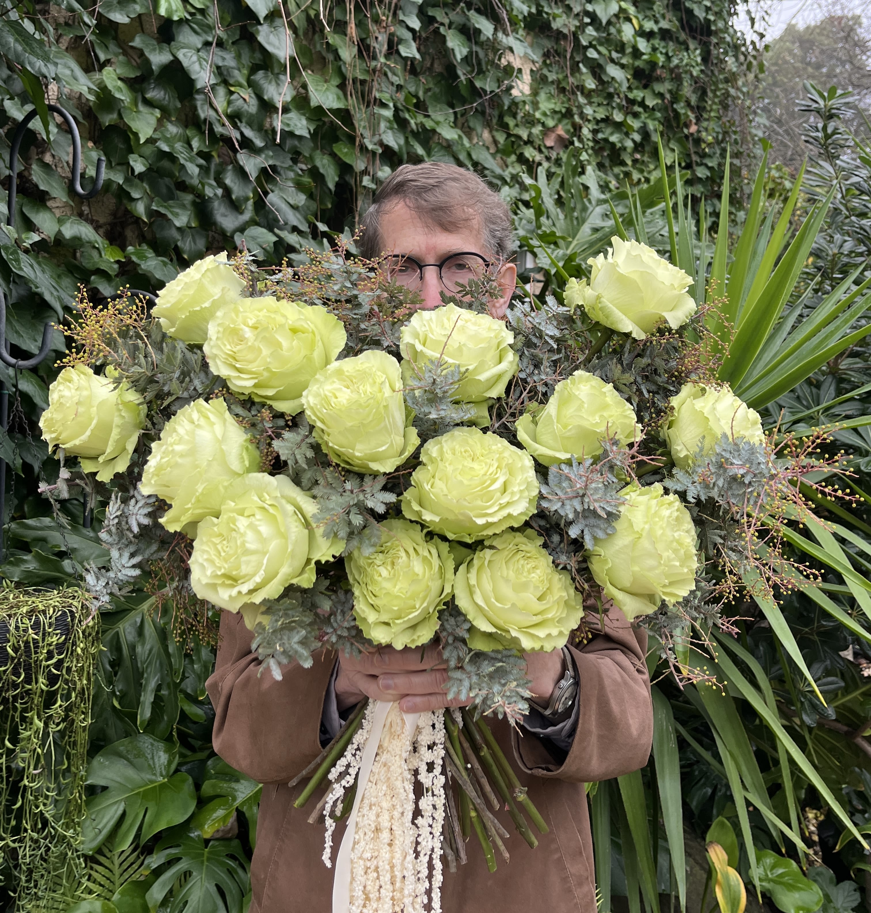 Person holding a large bouquet of pale green roses