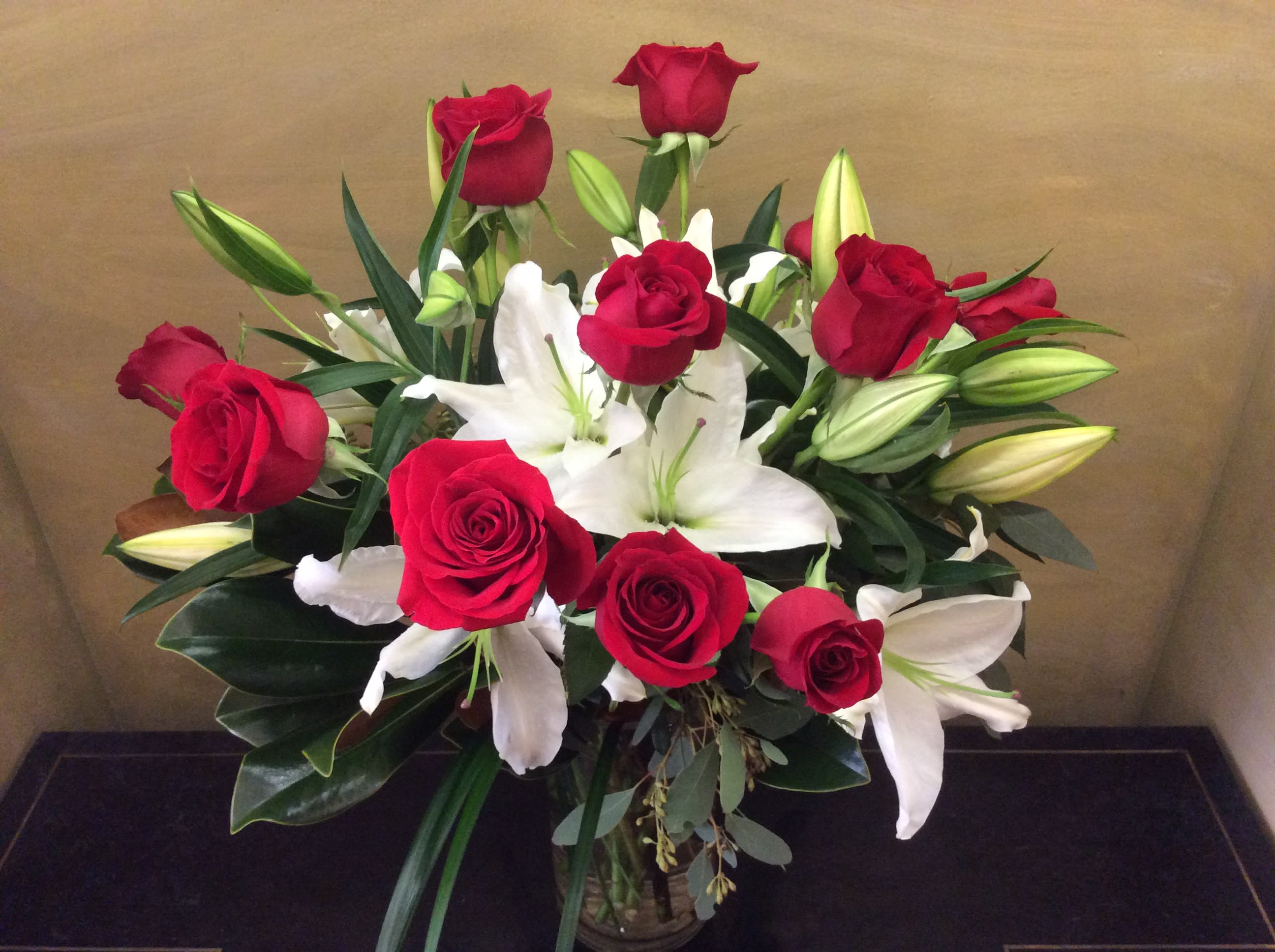 Red roses and white lilies arranged in a glass vase