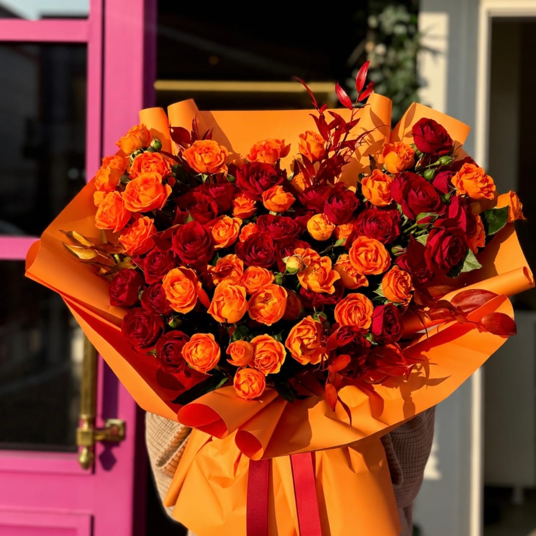 Large bouquet of red and orange roses wrapped in orange paper