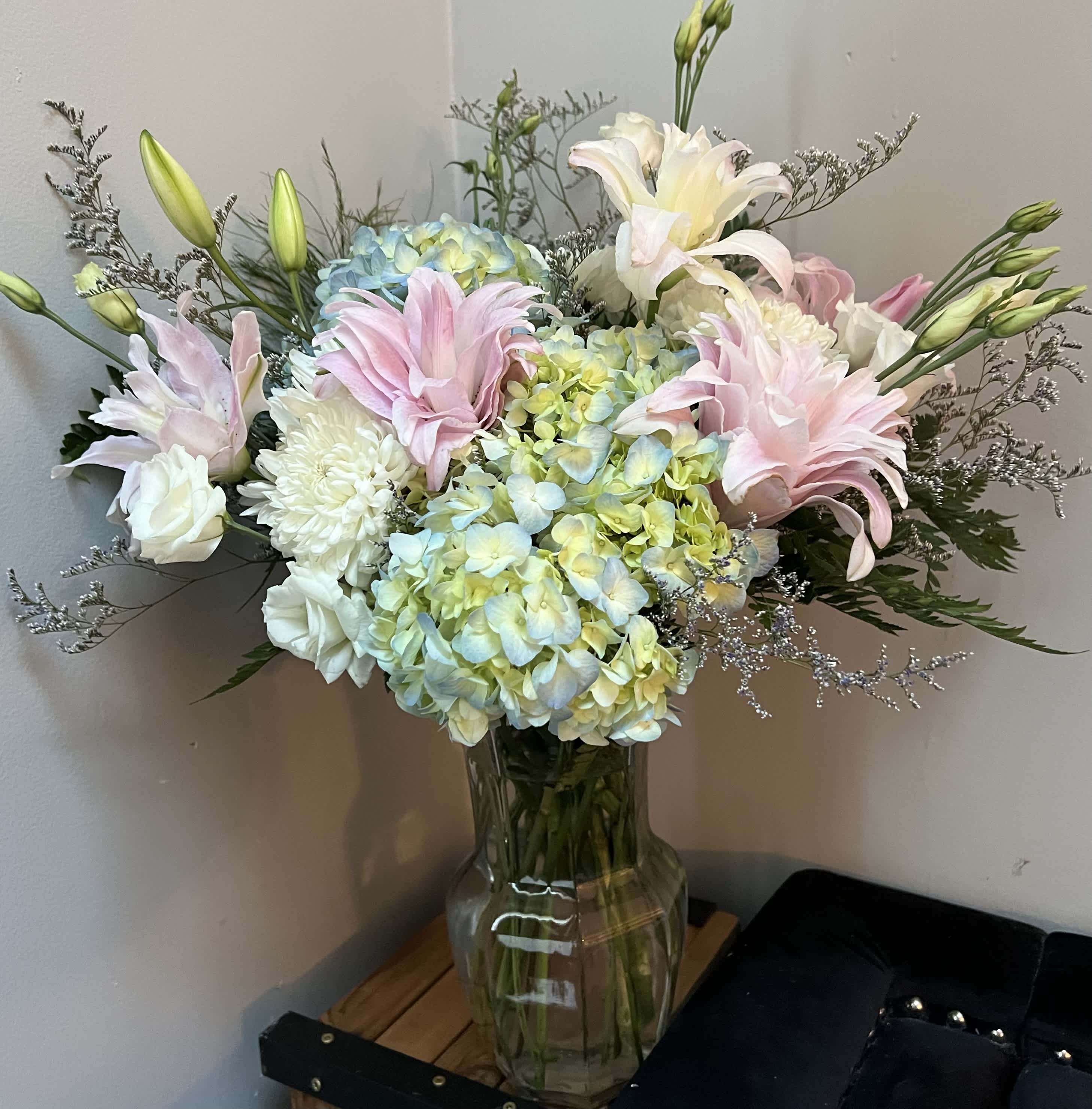 Pastel bouquet of lilies, hydrangeas, and white blooms in a glass vase