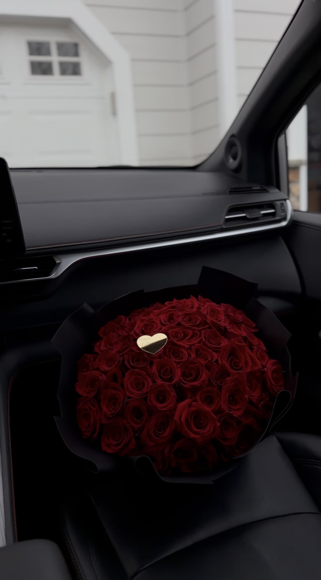 Bouquet of red roses with a small gold heart in black wrap
