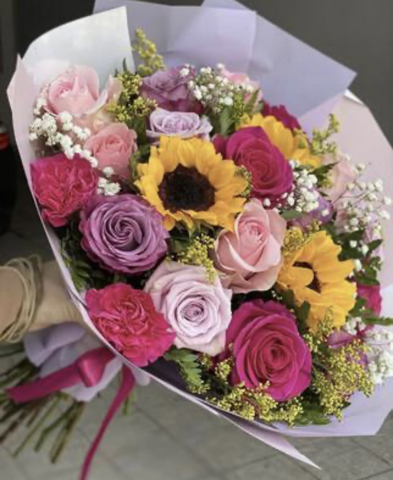 Bouquet of pink and purple roses with sunflowers in pastel wrapping