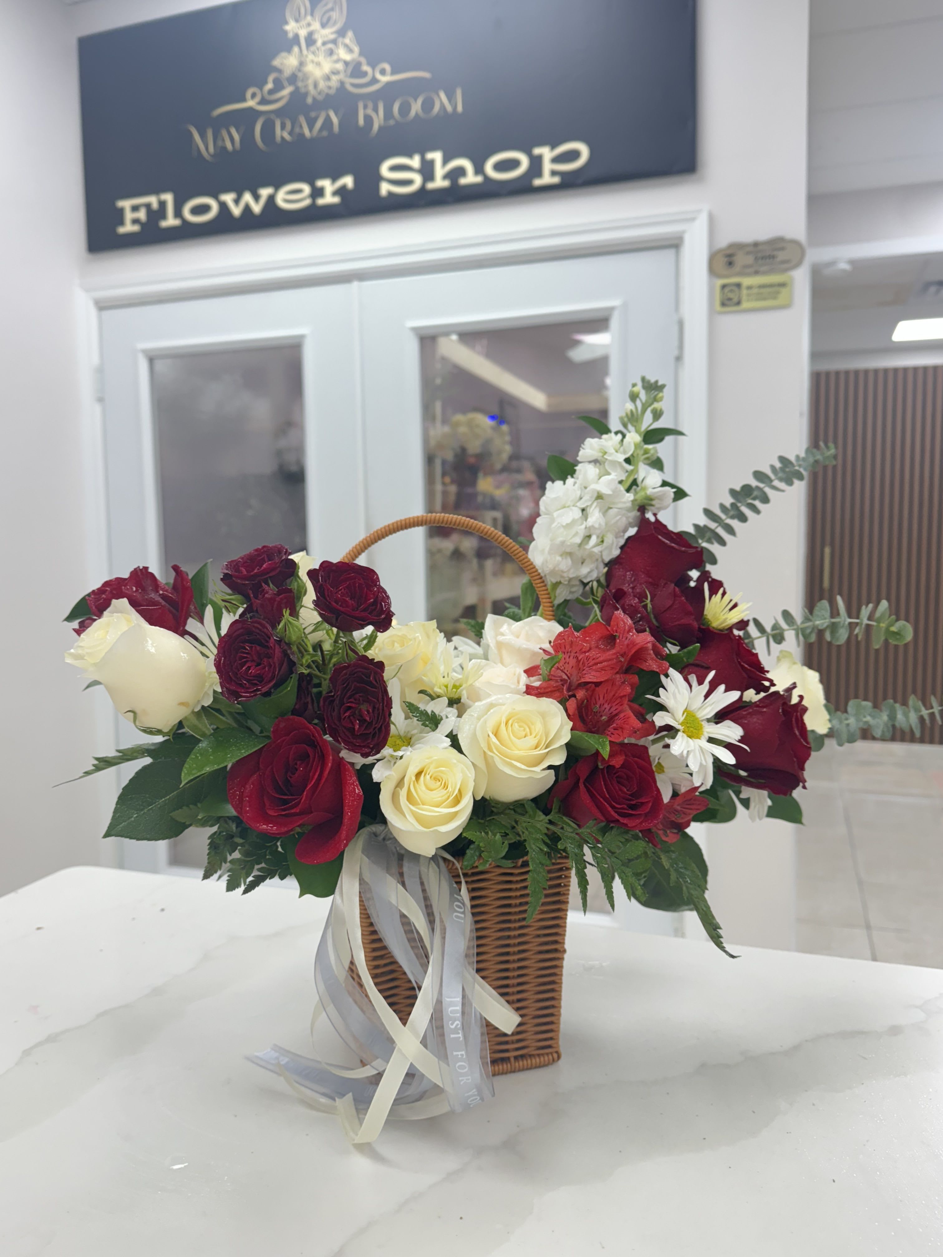 Basket arrangement of red and white roses with daisies