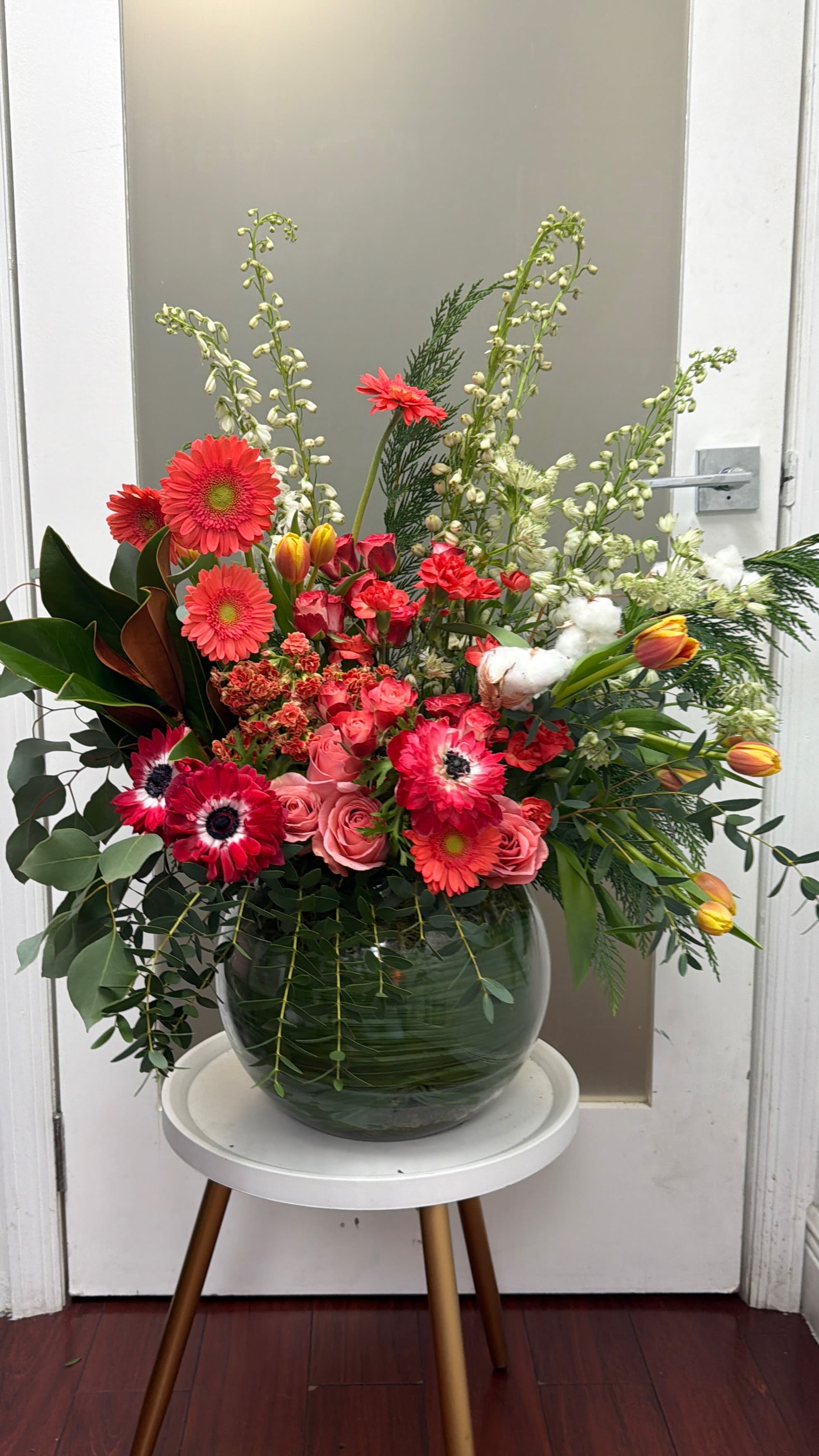 Large mixed flower arrangement in a glass vase with pink and red blooms