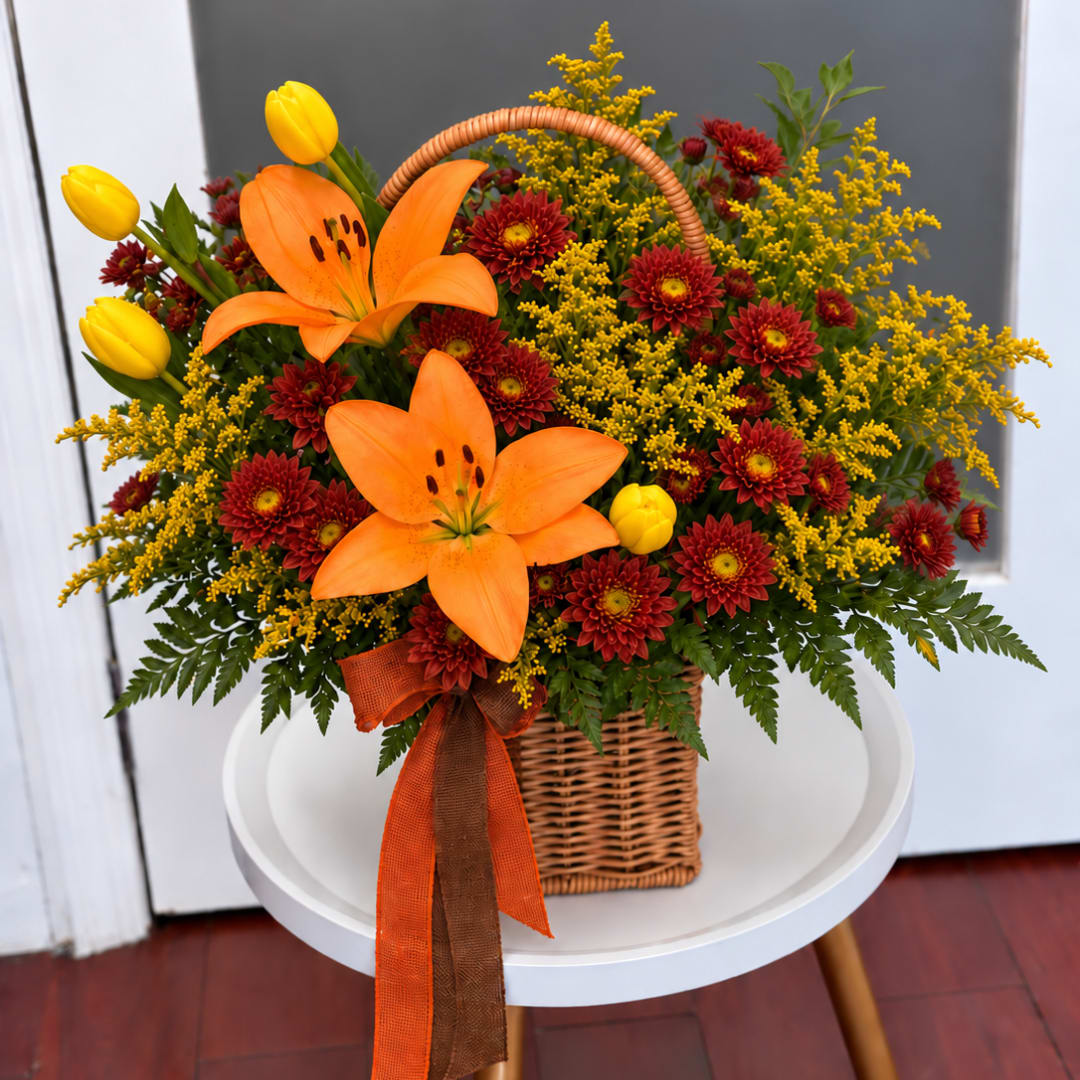 Basket arrangement with orange lilies, yellow tulips, and red mums