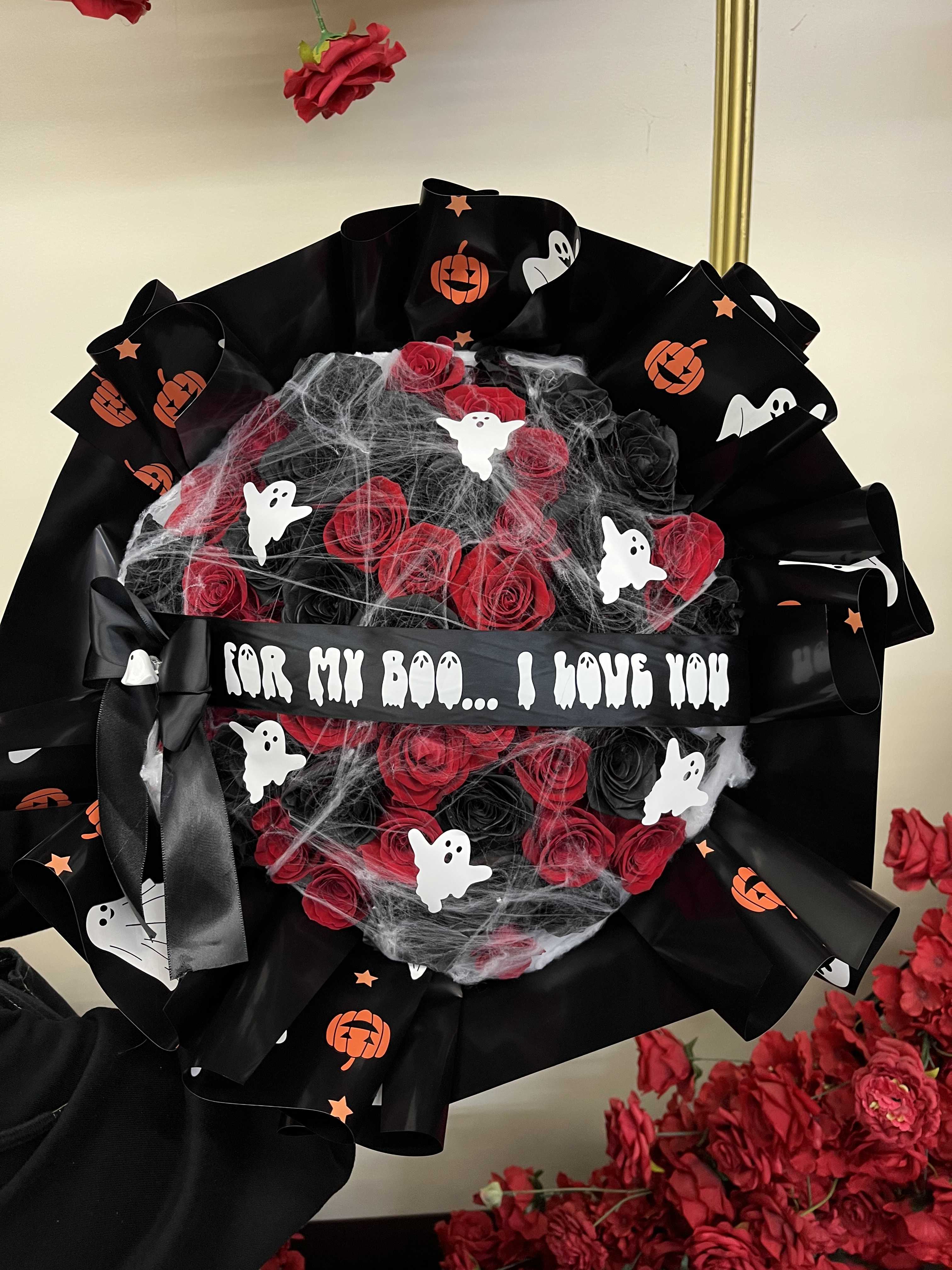 Halloween bouquet of red roses wrapped in black ribbon with ghost decorations