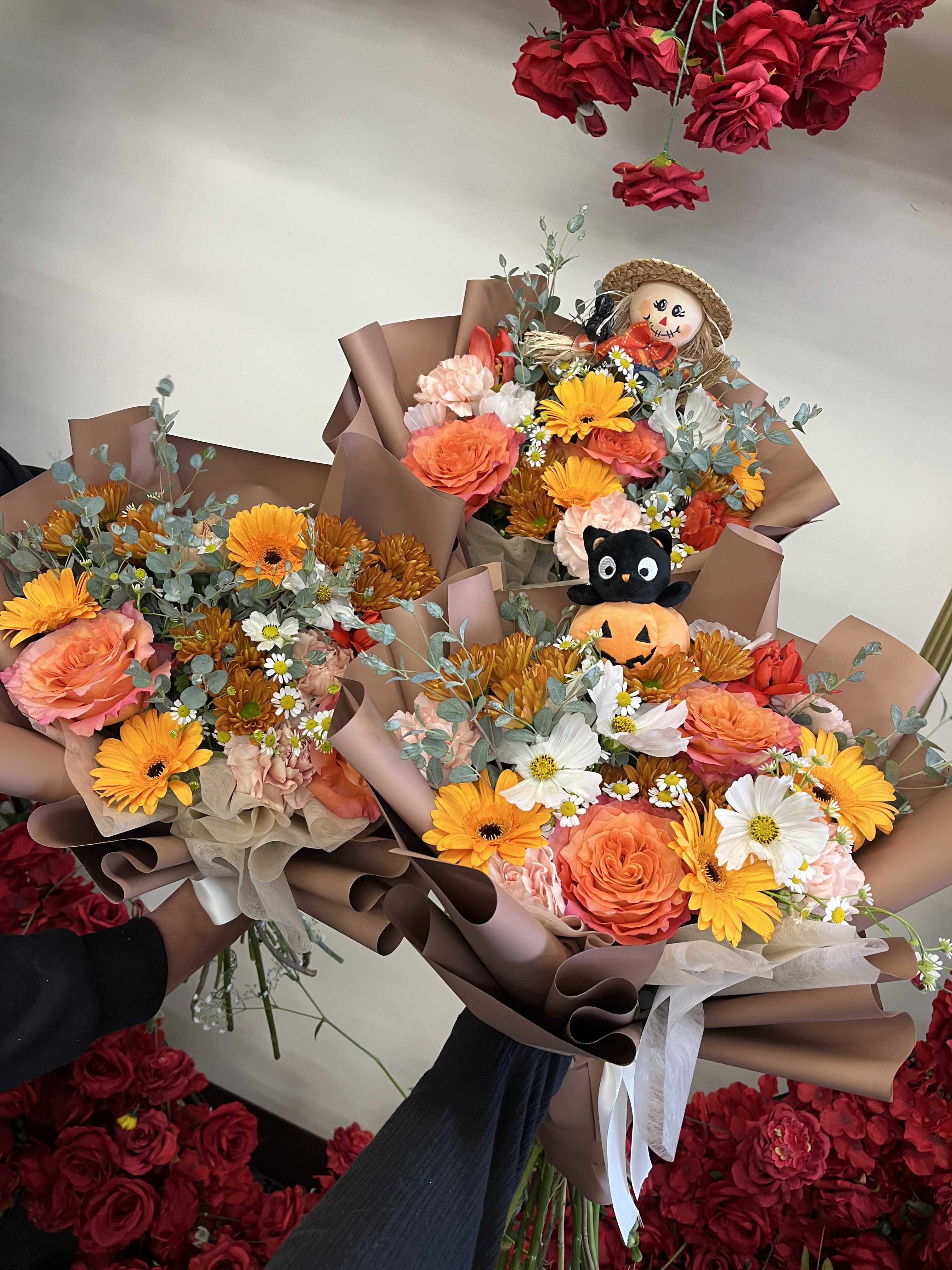 Three mixed flower bouquets with a small plush pumpkin cat and scarecrow topper