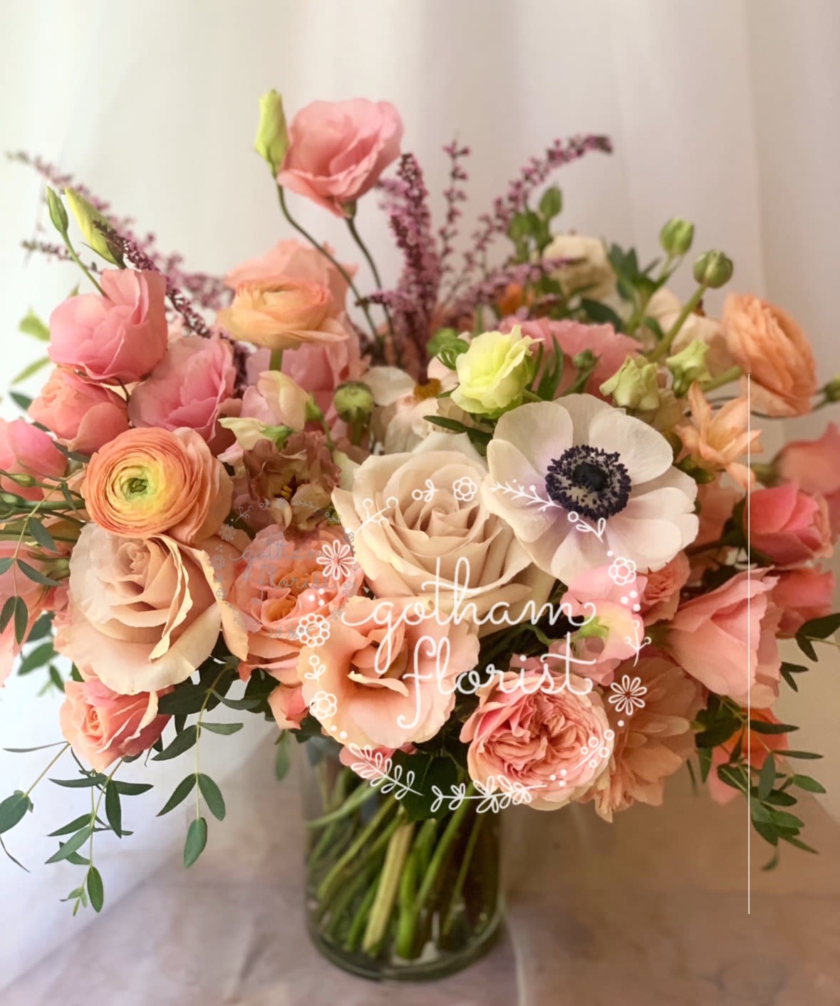 Pink and peach bouquet with roses and anemones in a glass vase
