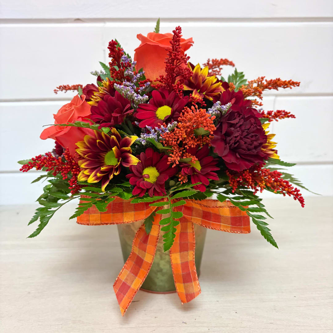 Autumn bouquet of red and orange flowers in a vase with plaid ribbon