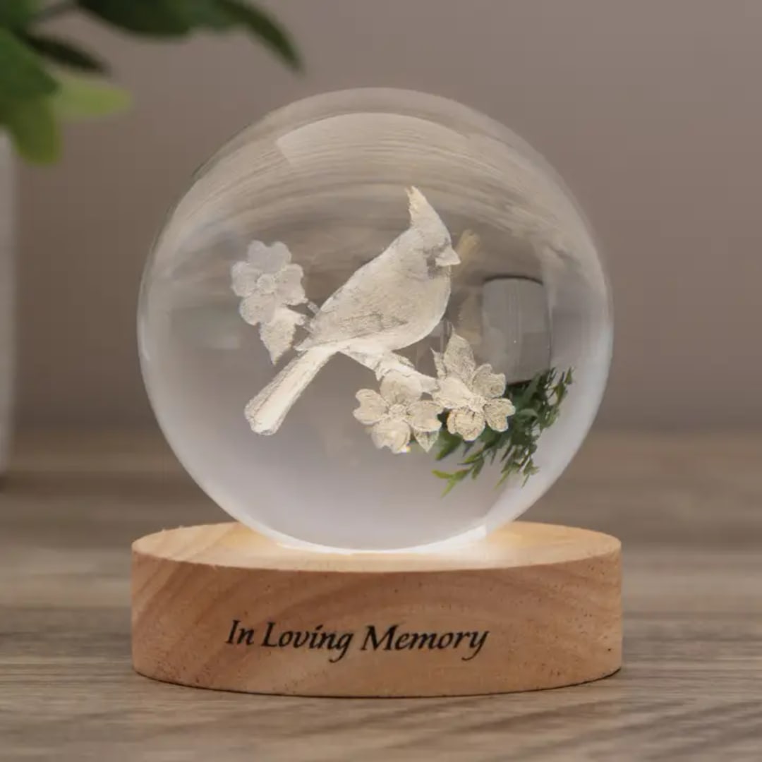 Glass orb with a white bird and flowers on a wooden base