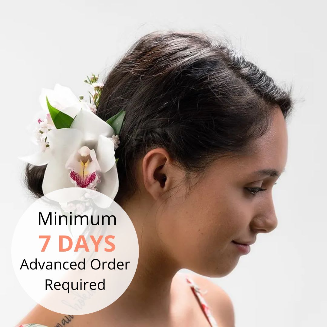 White orchid hair flower worn behind the ear on a woman with dark hair in profile