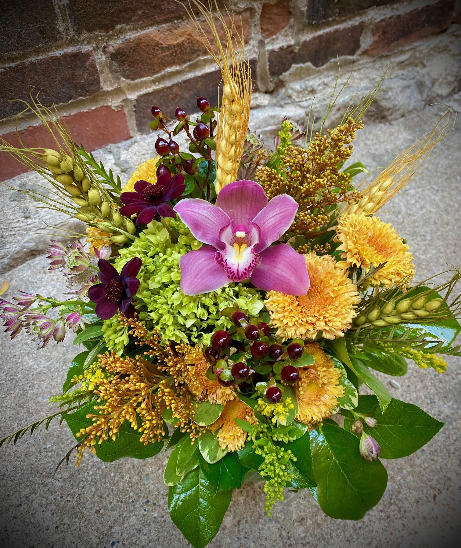 Mixed bouquet with pink orchid, yellow mums, and wheat stems