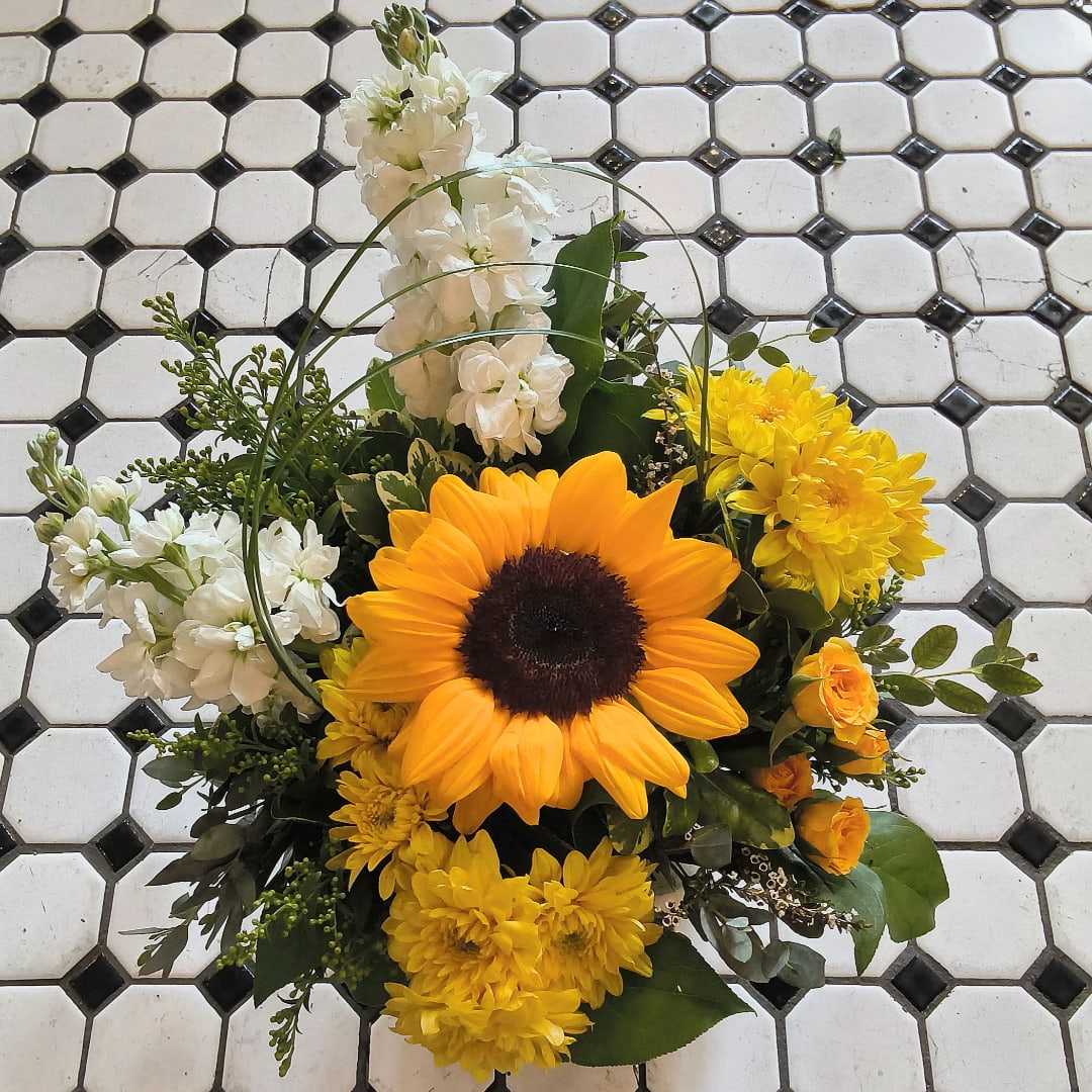 Sunflower arrangement with white and yellow flowers on a tiled surface
