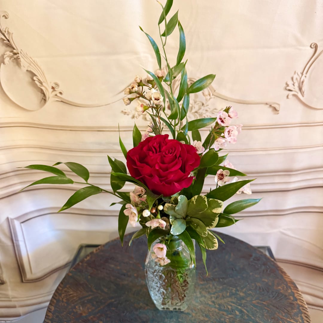 Red rose arrangement in a clear glass vase with small pink accent flowers