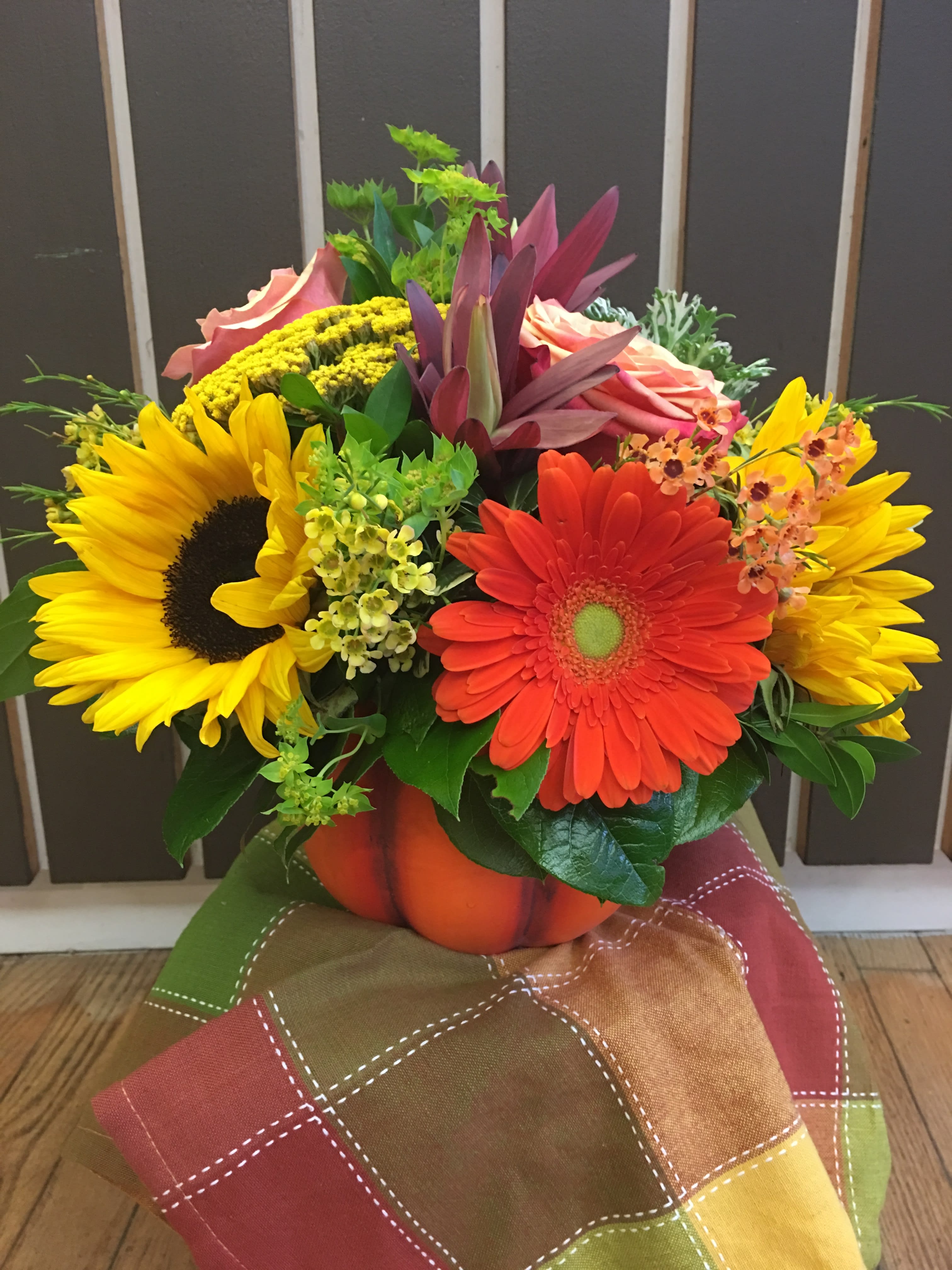 Bright mixed bouquet with sunflowers and gerbera daisies in a pumpkin vase