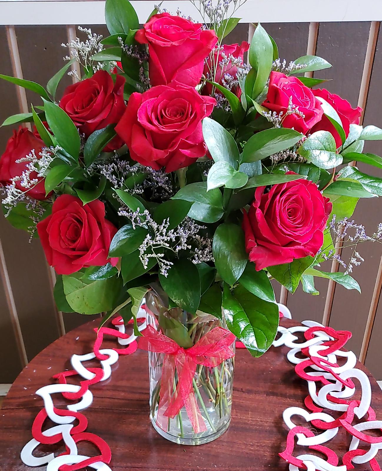 Bouquet of red roses in a clear glass vase with a red ribbon