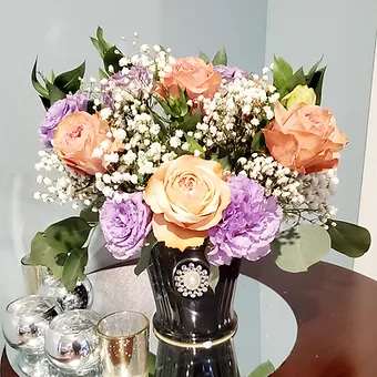 Black and pearl ceramic styled - Country peach roses, babysbreath and ocean song roses in lavender complete this soft, yet colorful floral display.  Comes in a beautiful black container with diamond and pear accents.