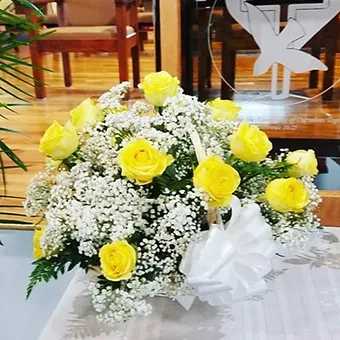 Floral Basket - two dozen premium roses and babysbreath adorned with vibrant greenery in a round flat basket with a bow.  Perfect for any memorial service or as a gift, this vibrant arrangment really draws attention.
