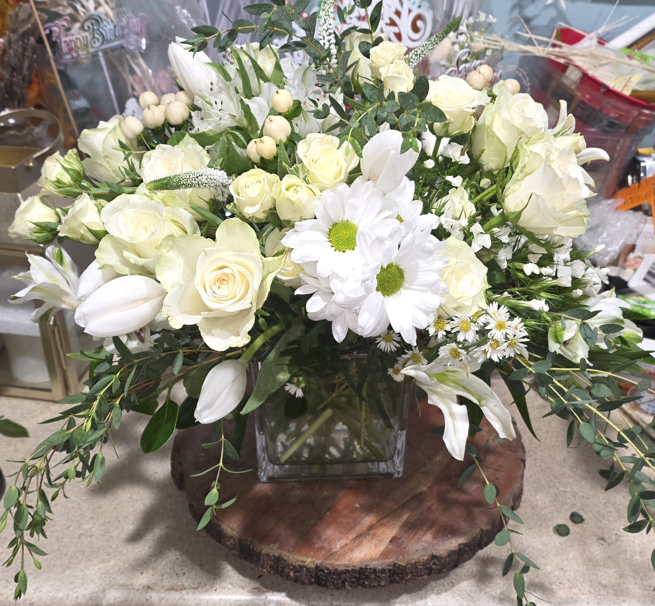 Aubrey - Beautiful all white arrangement. Can be sent as a sympathy gift or as an event arrangement.  White Tulip, white roses, weeping parvafolia, aster,, mum, alstroemeria and white sweet William in a clear 5 inch glass cube. 