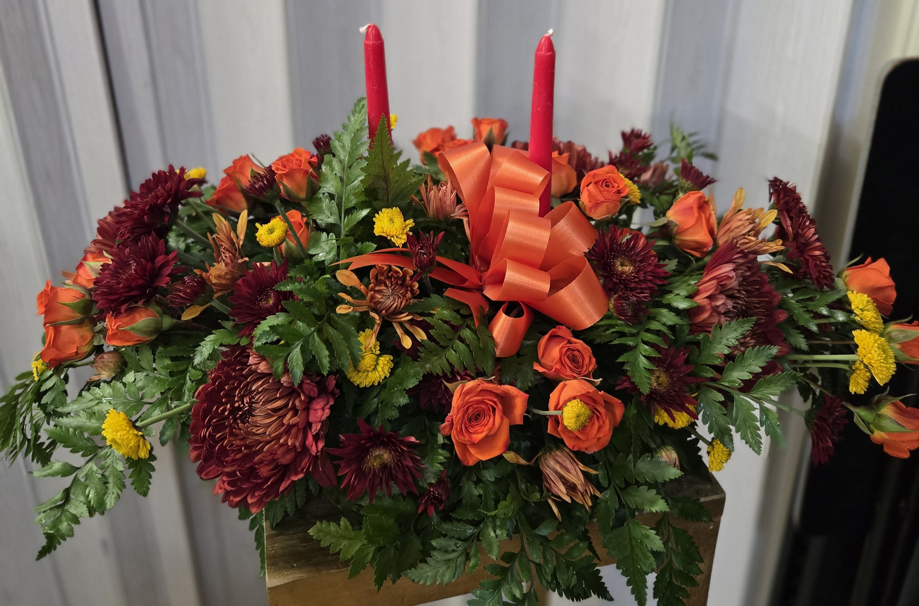 Autumn candle centerpiece  - orange roses, burgundy chrysanthemums, yellow button mums, and lush greenery.
