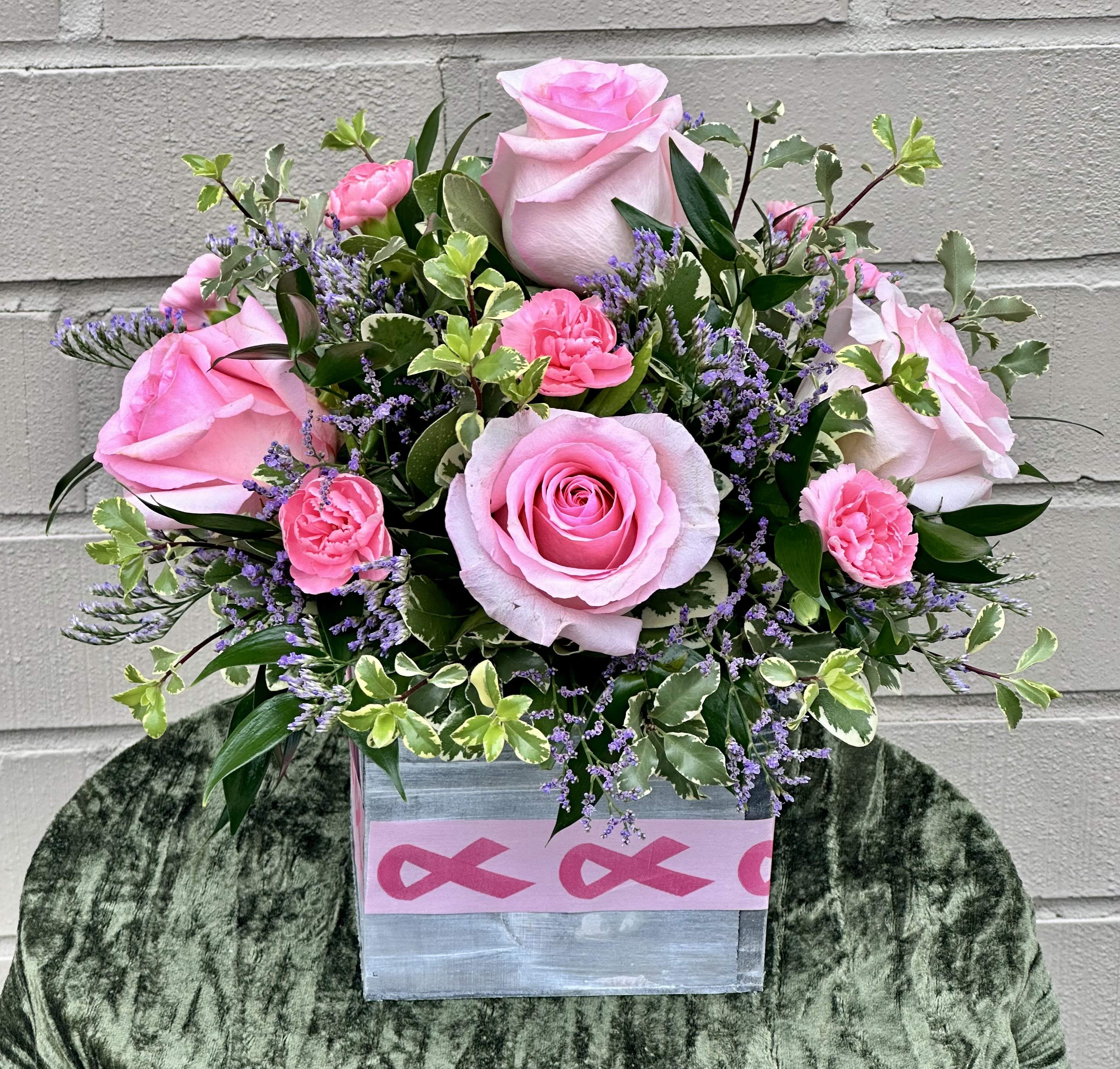 Pink roses and carnations in a square box with purple filler flowers.