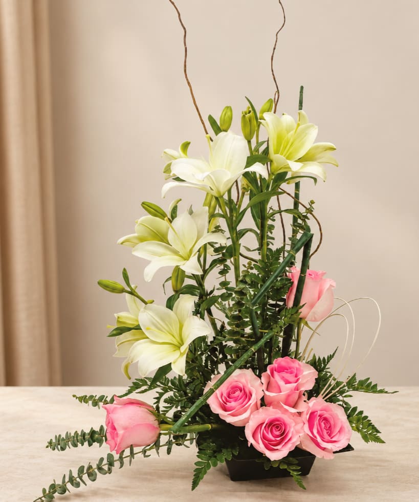 Pink roses and white lilies arranged in a black vase