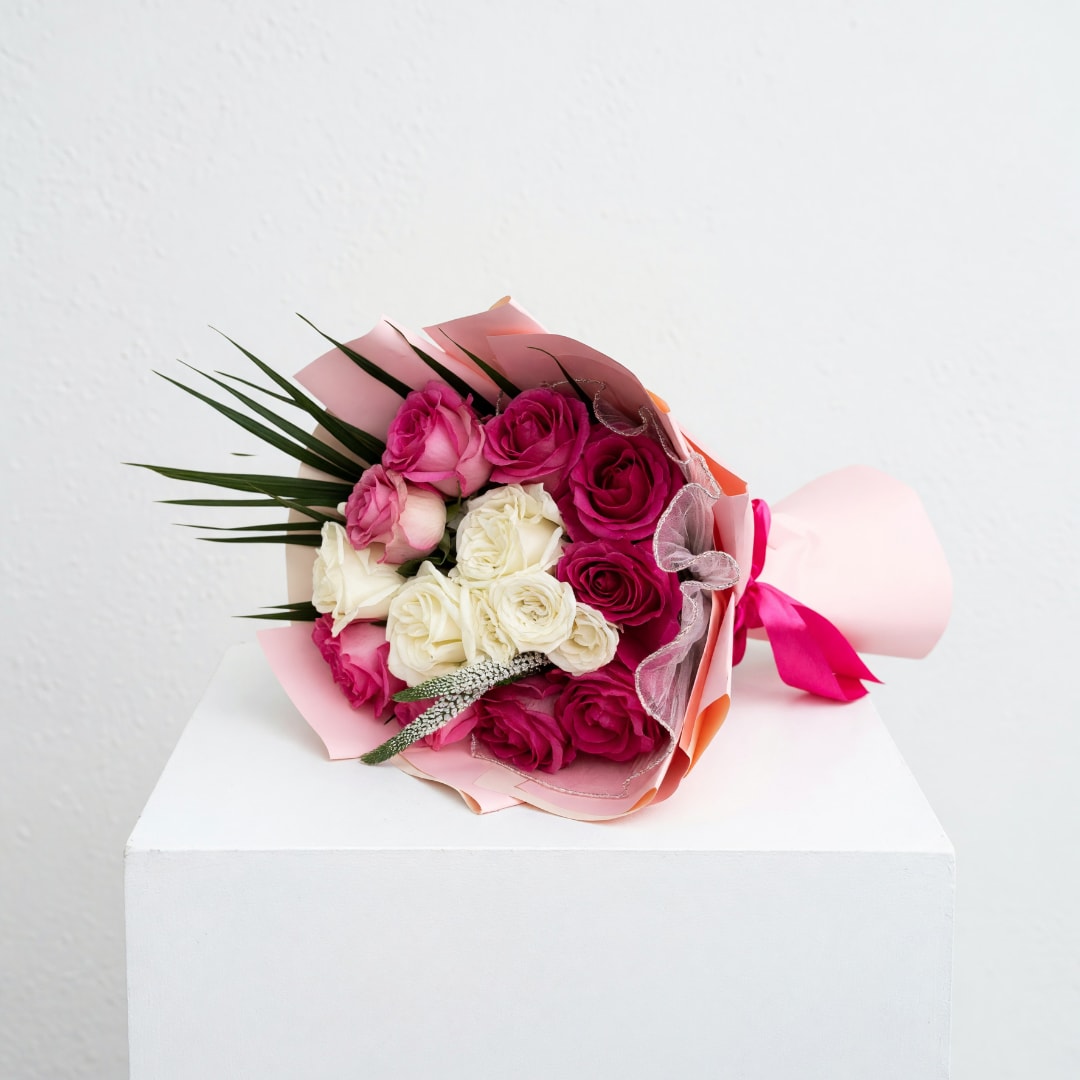 Bouquet of pink and white roses wrapped in pink paper