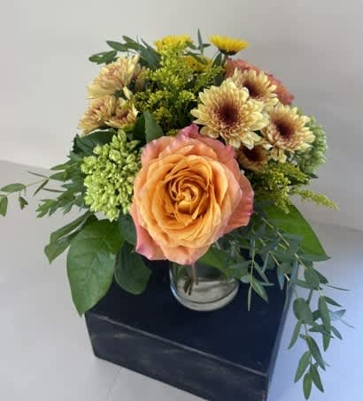 Peach rose bouquet with yellow chrysanthemums in a glass vase