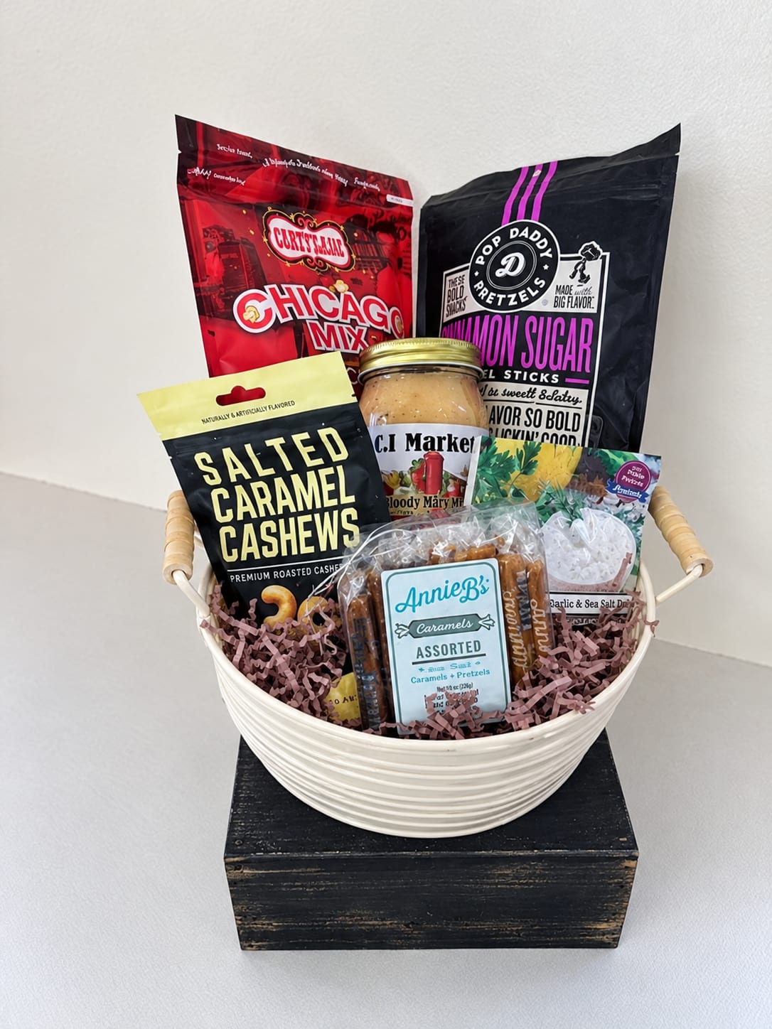 Gift basket with assorted snack bags and a jar in a white bowl