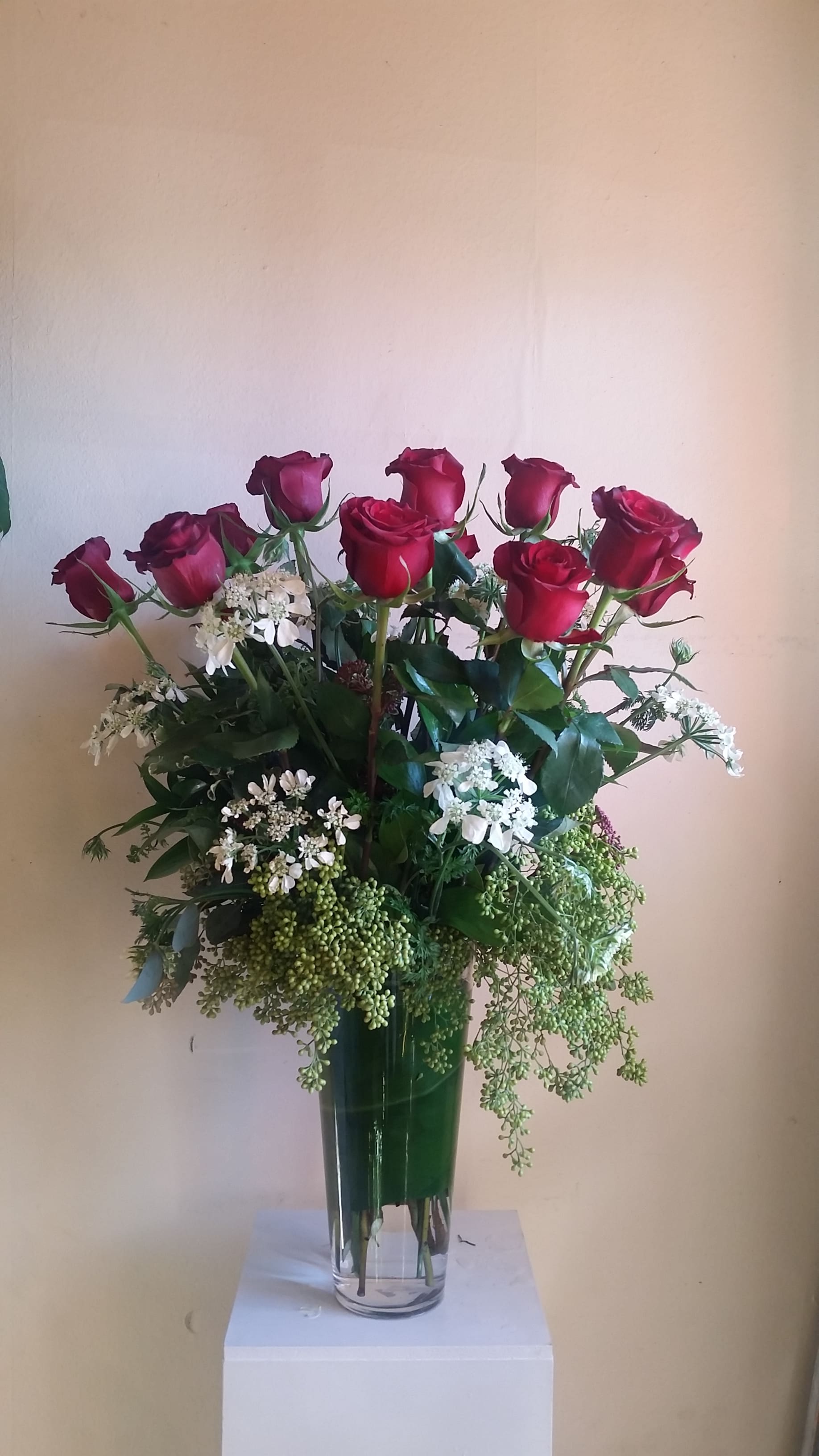 Tall vase arrangement of red roses and white filler flowers