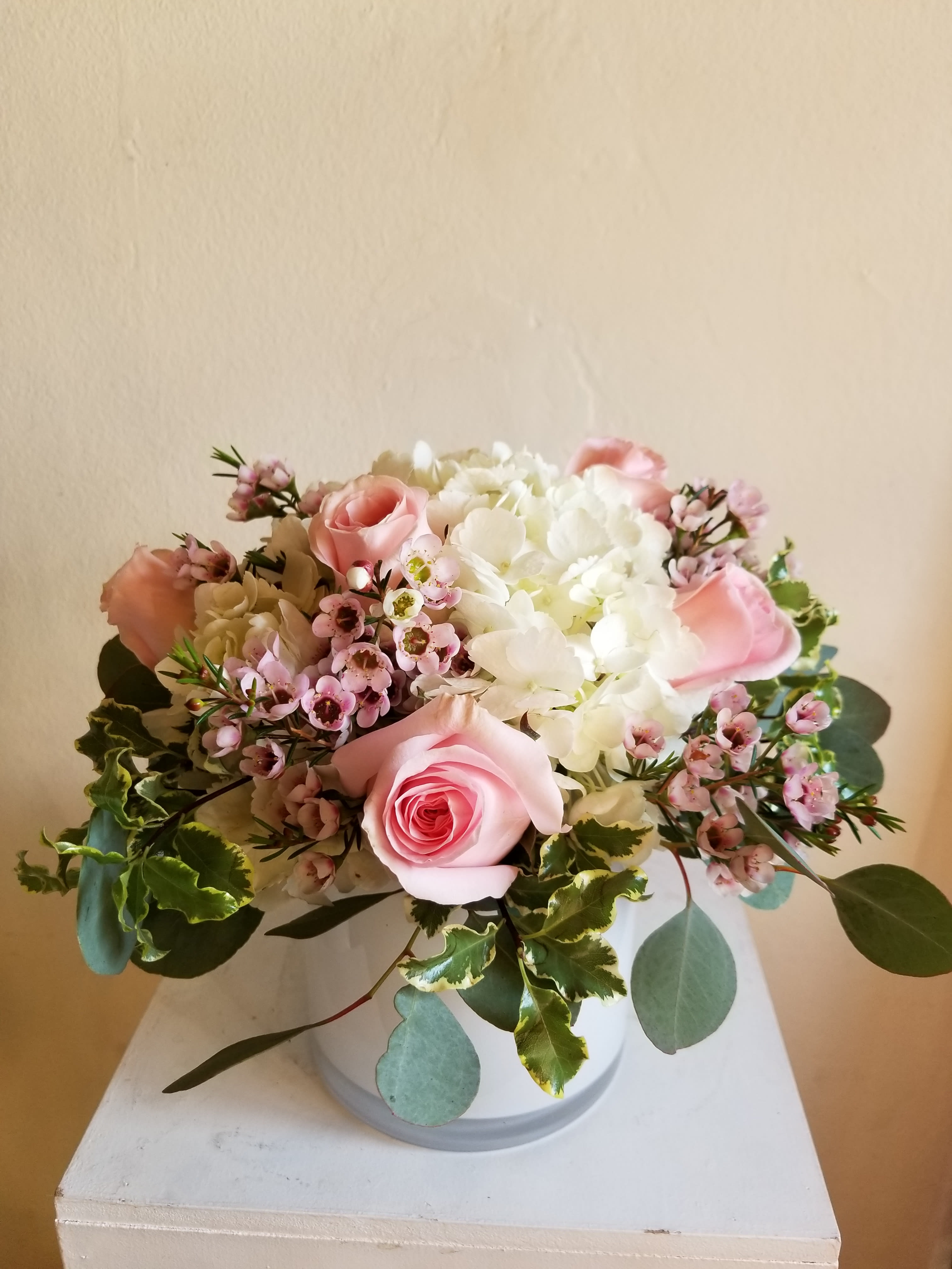 Pink roses and white hydrangeas arranged in a white vase