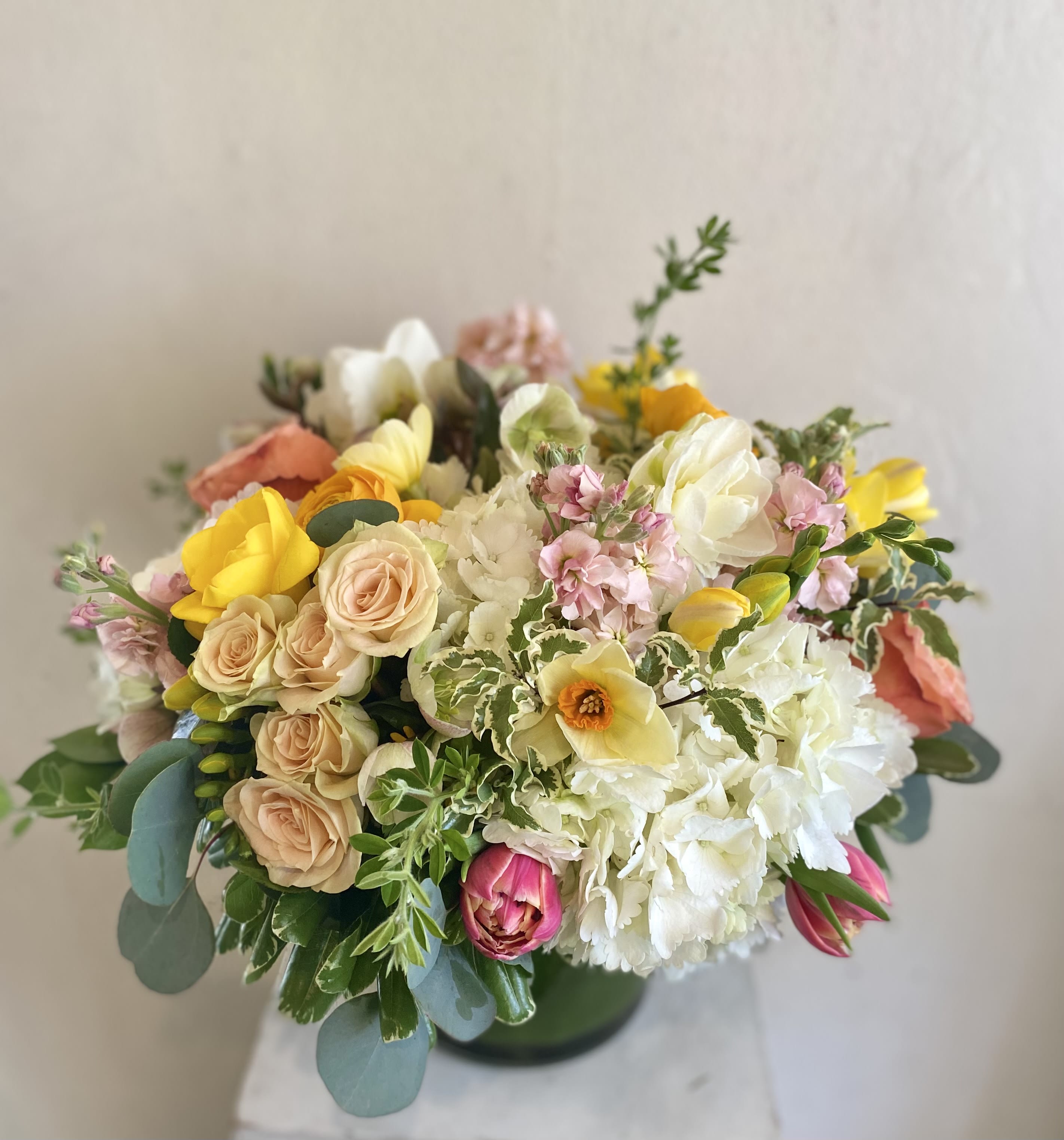 Mixed bouquet of pastel roses, tulips, and white blooms in a vase