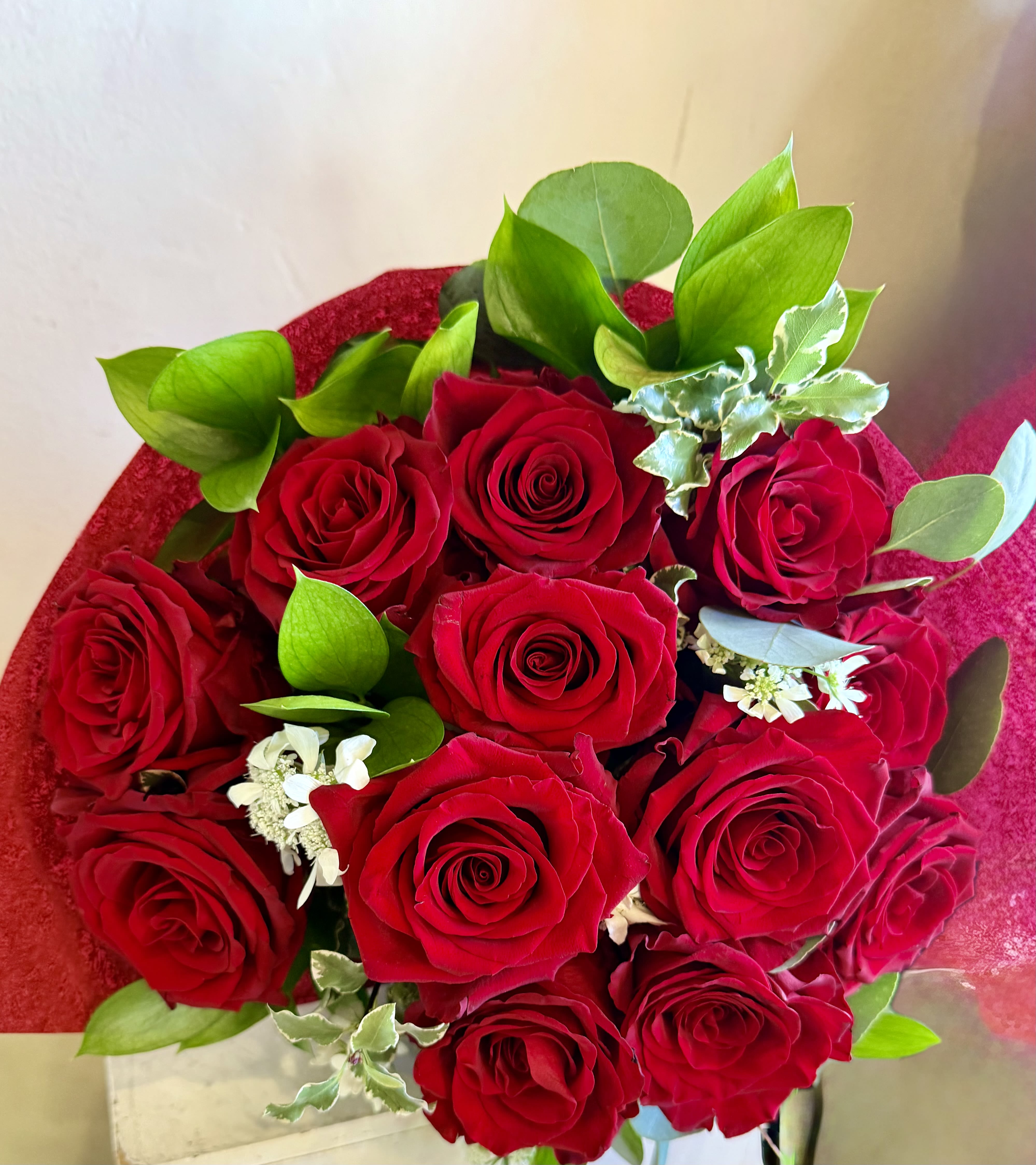 Bouquet of red roses with green foliage and small white filler flowers