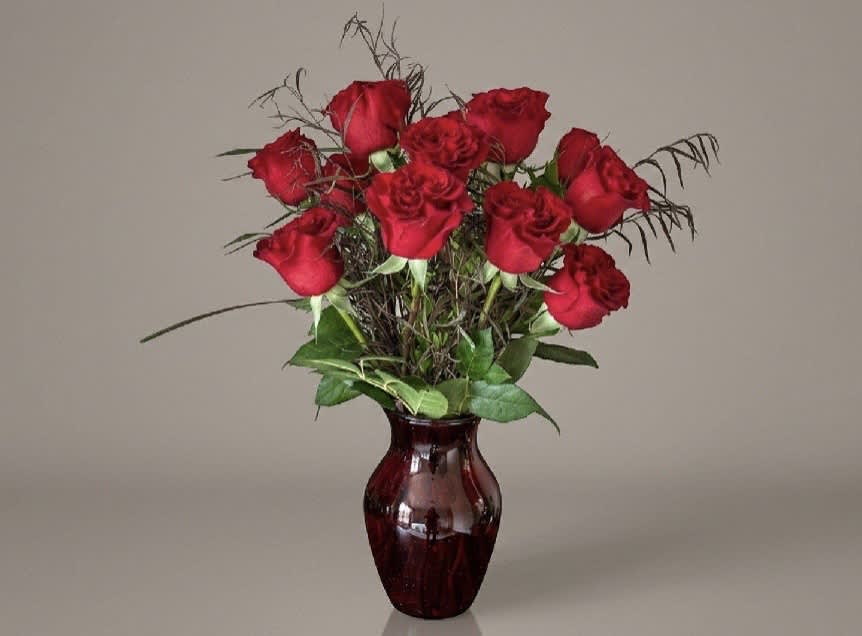 Red roses arranged in a burgundy glass vase