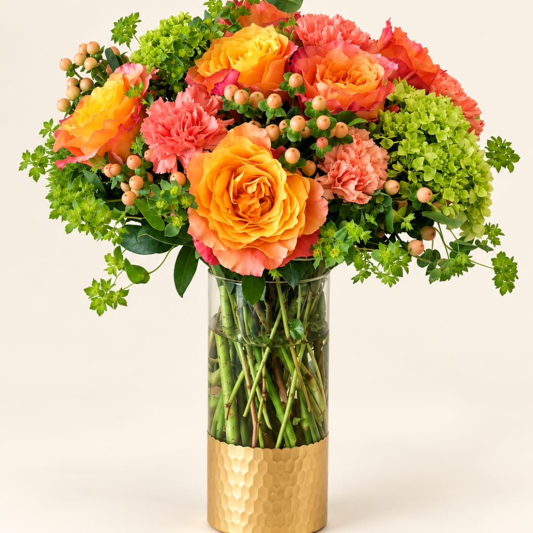 Orange and coral roses with pink carnations in a glass vase