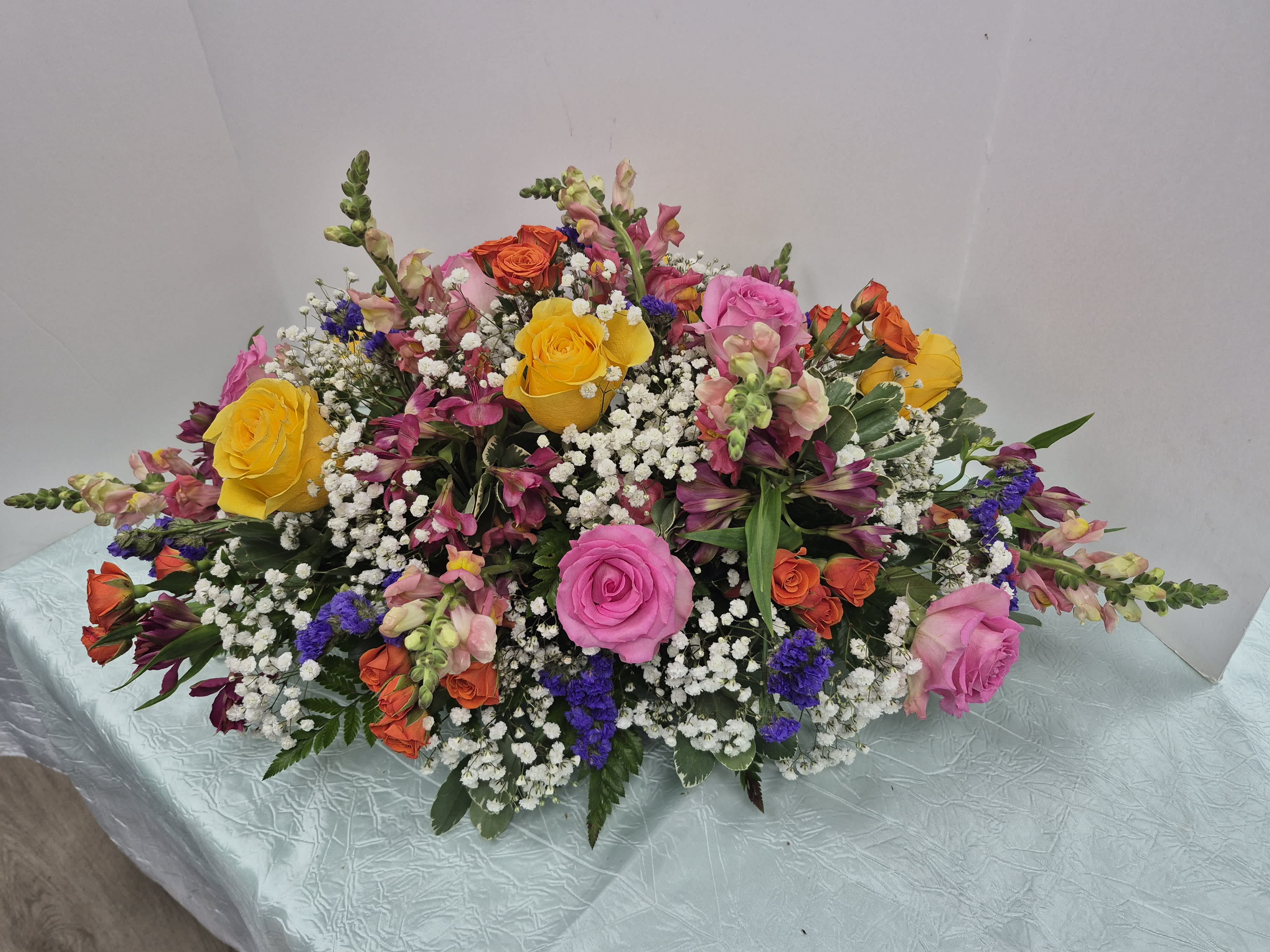 Large mixed bouquet with pink, yellow, and orange roses and small white filler flowers