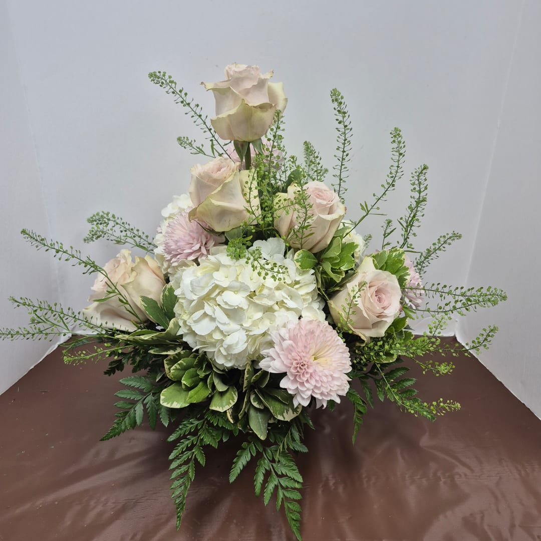 Arrangement of pale roses, white hydrangea, and pink mums in a low design