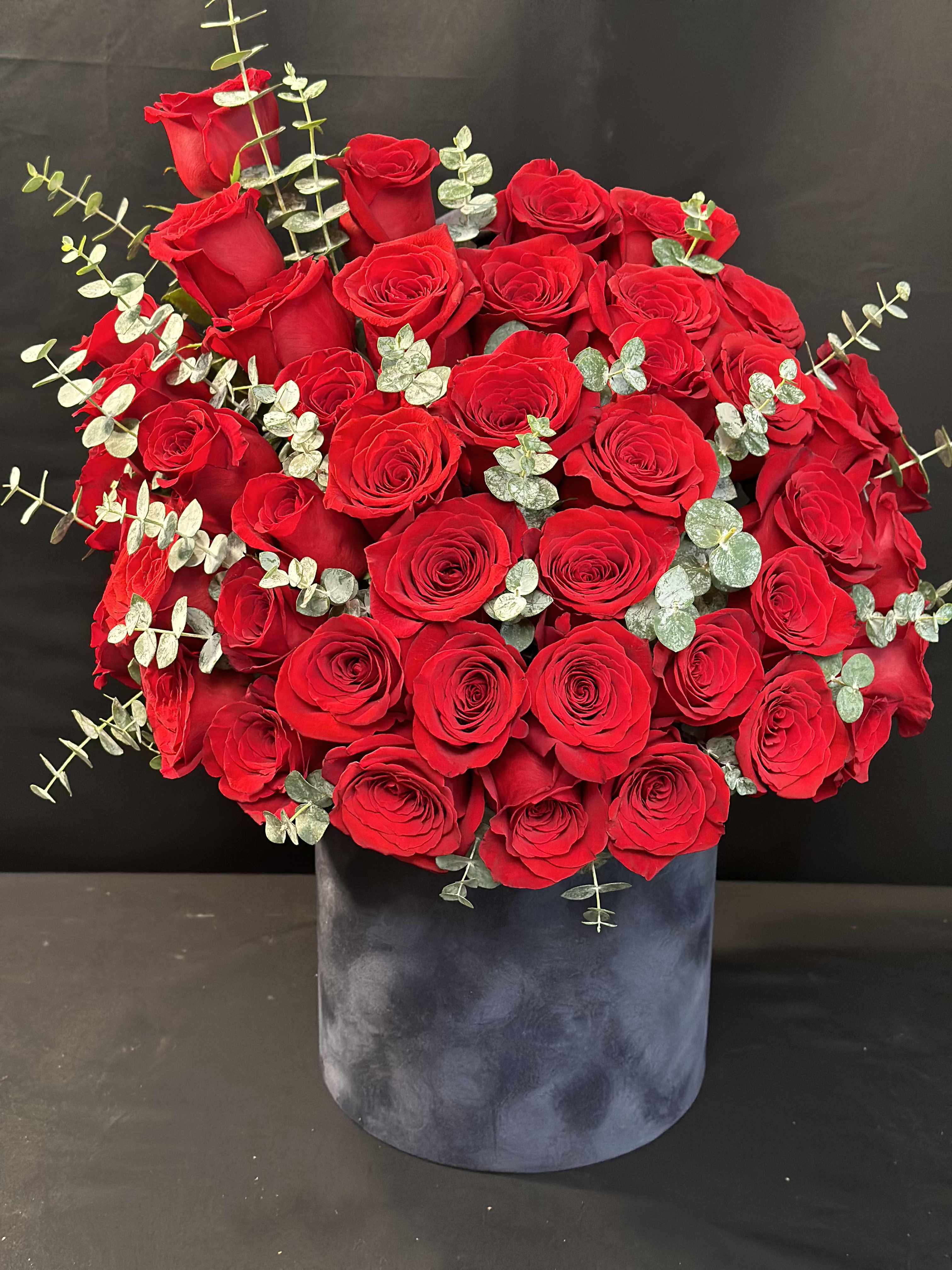 Large bouquet of red roses in a dark velvet box
